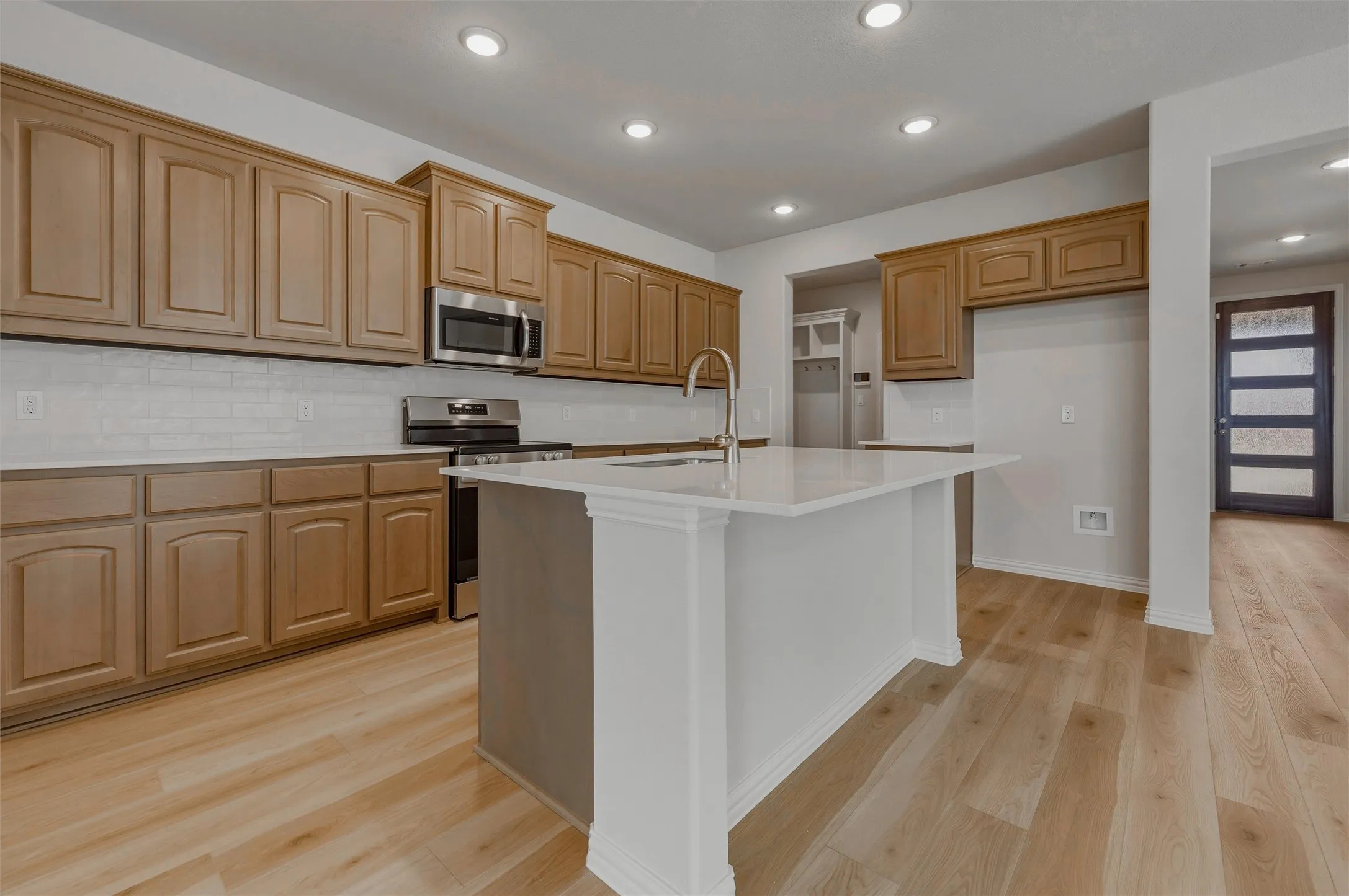 Kitchen featuring wood-finish flooring, wood cabinetry, a center island with a white countertop, stainless steel appliances, and recessed lighting