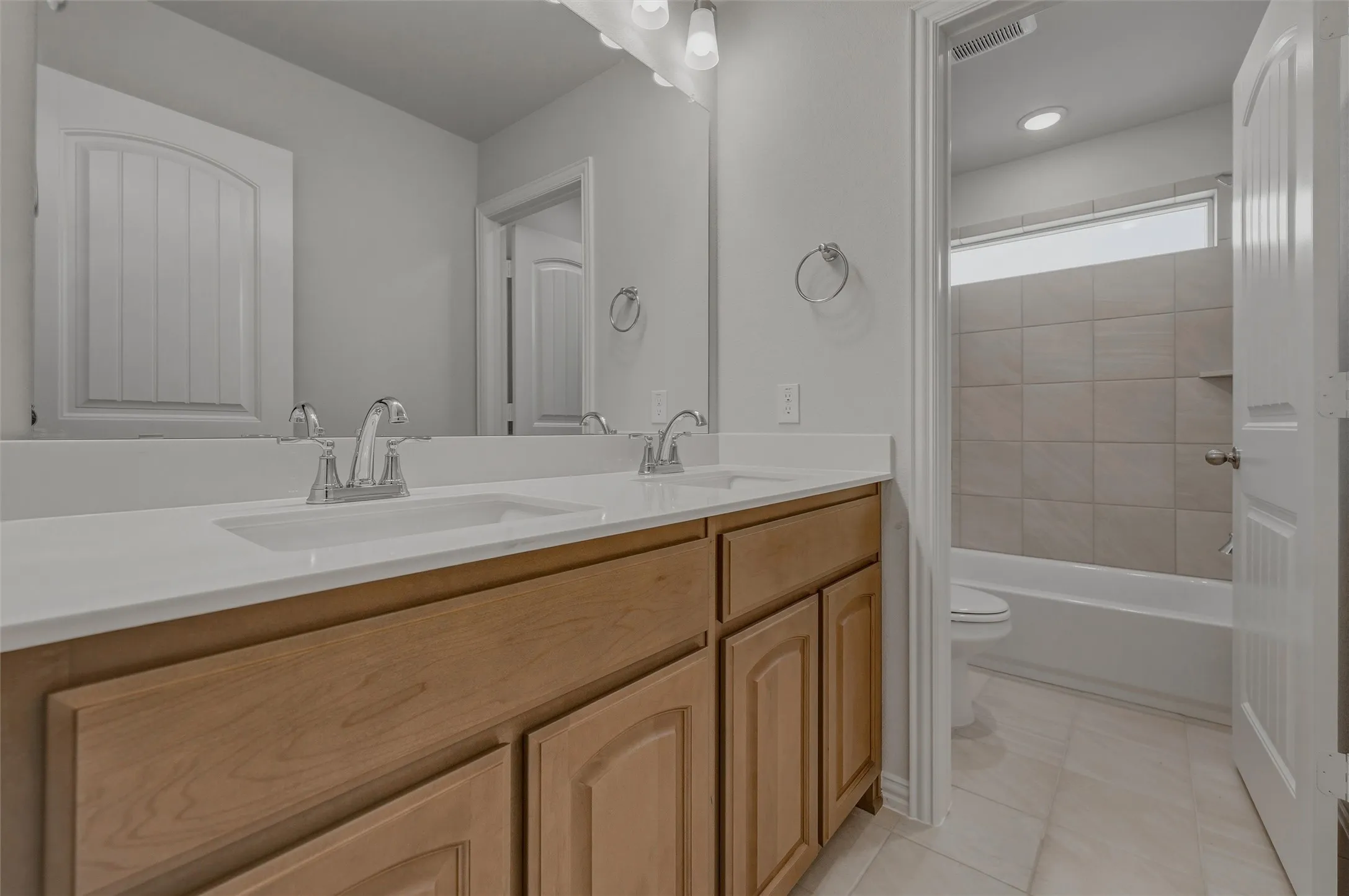 Dual vanity with white undermount sinks, chrome fixtures, and wood cabinetry