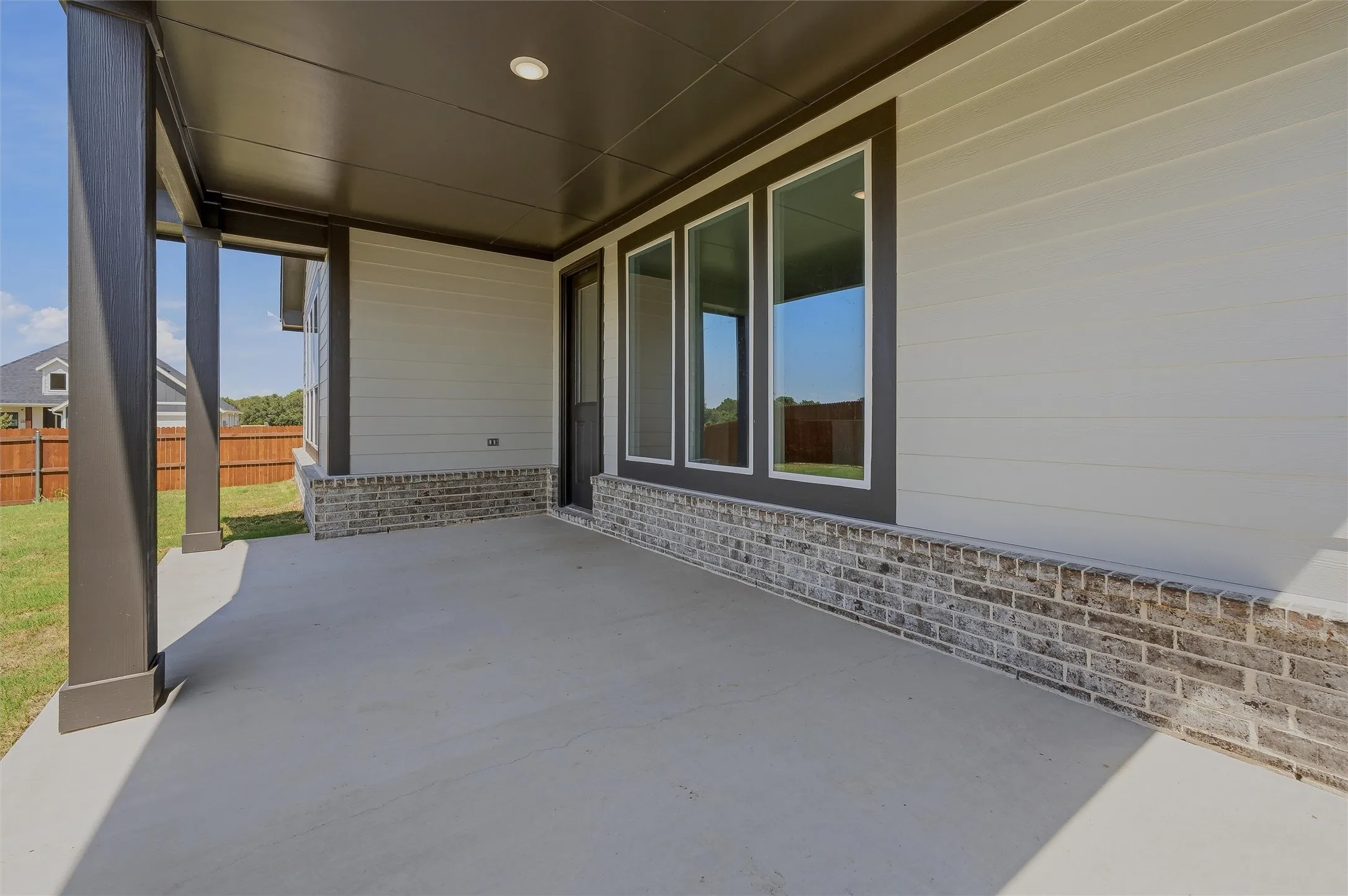 Covered patio with concrete flooring, brick wainscoting, siding exterior, and recessed lighting