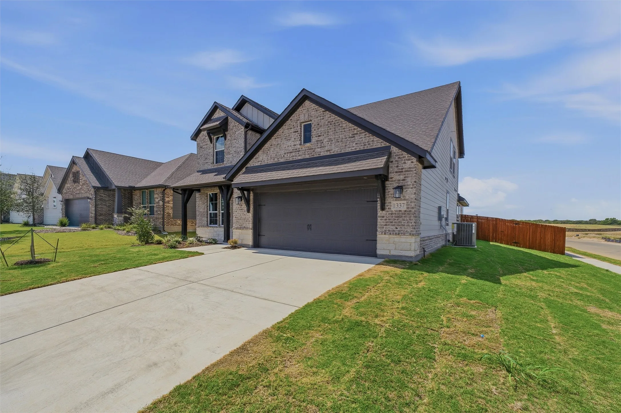 Two-story residence featuring a brick and siding exterior, a two-car garage, and a concrete driveway