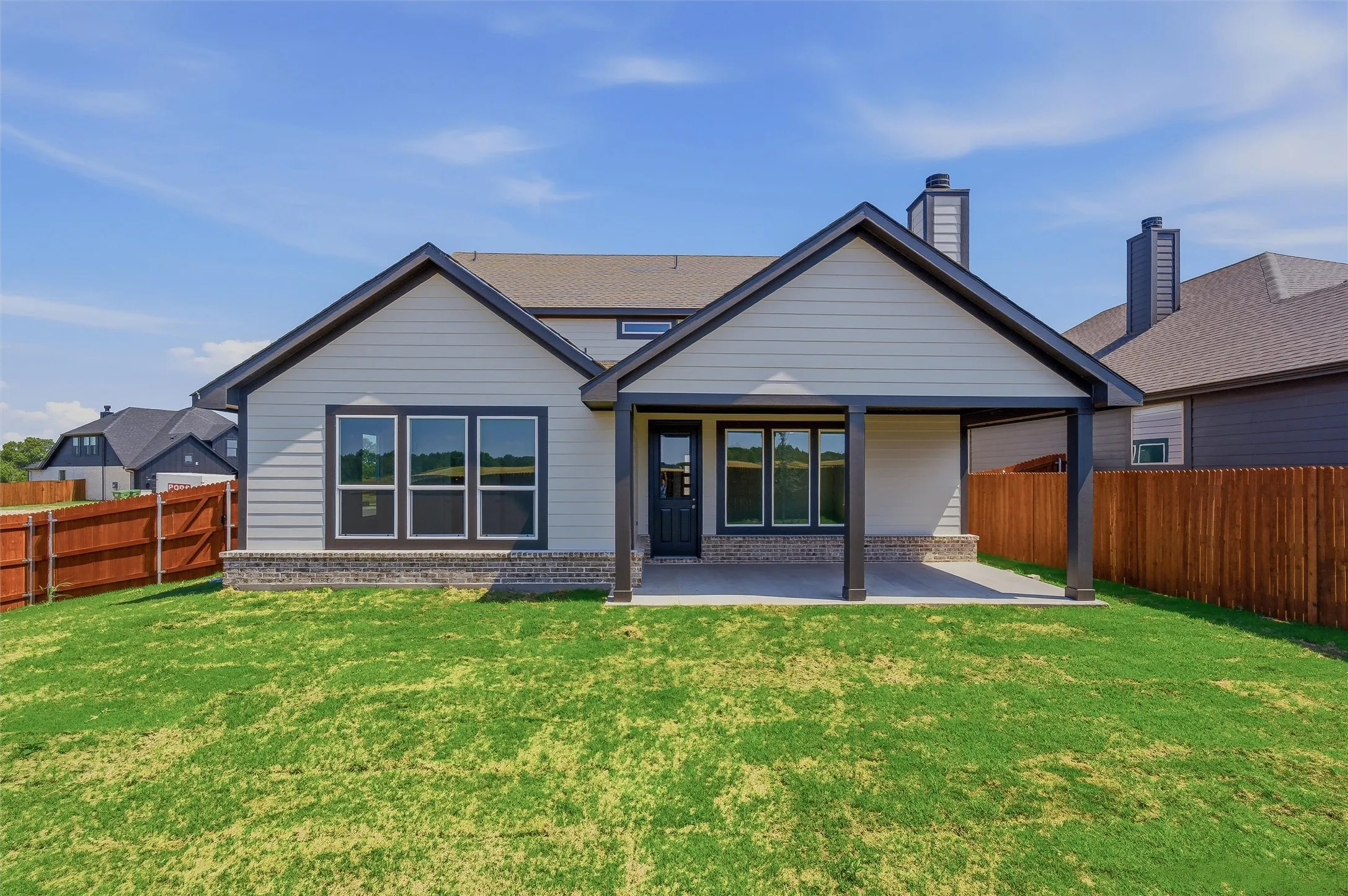 Spacious backyard featuring a manicured lawn, wood fencing, and a covered patio