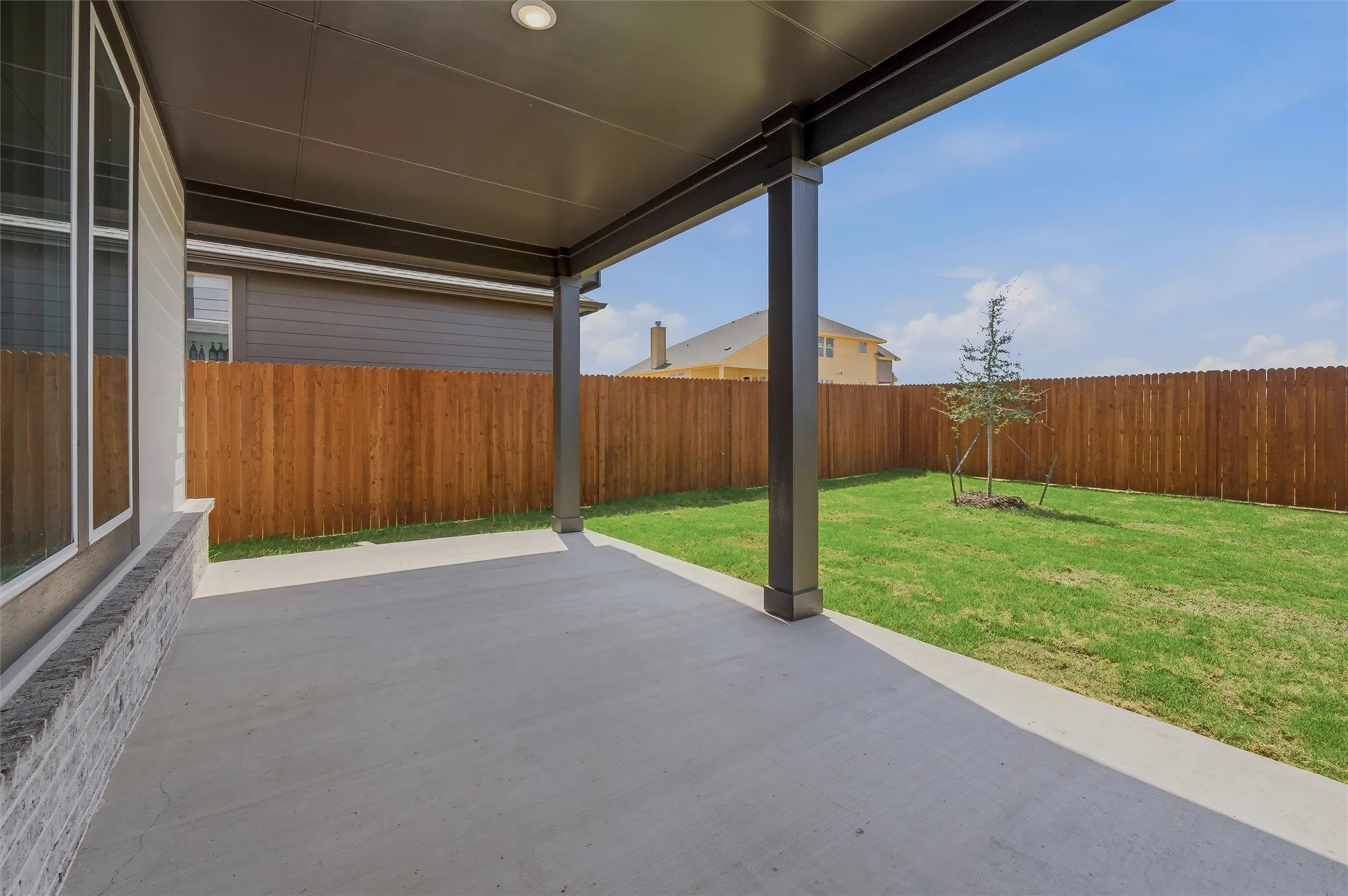 Covered patio with recessed lighting, concrete flooring, and a fenced backyard with a tree