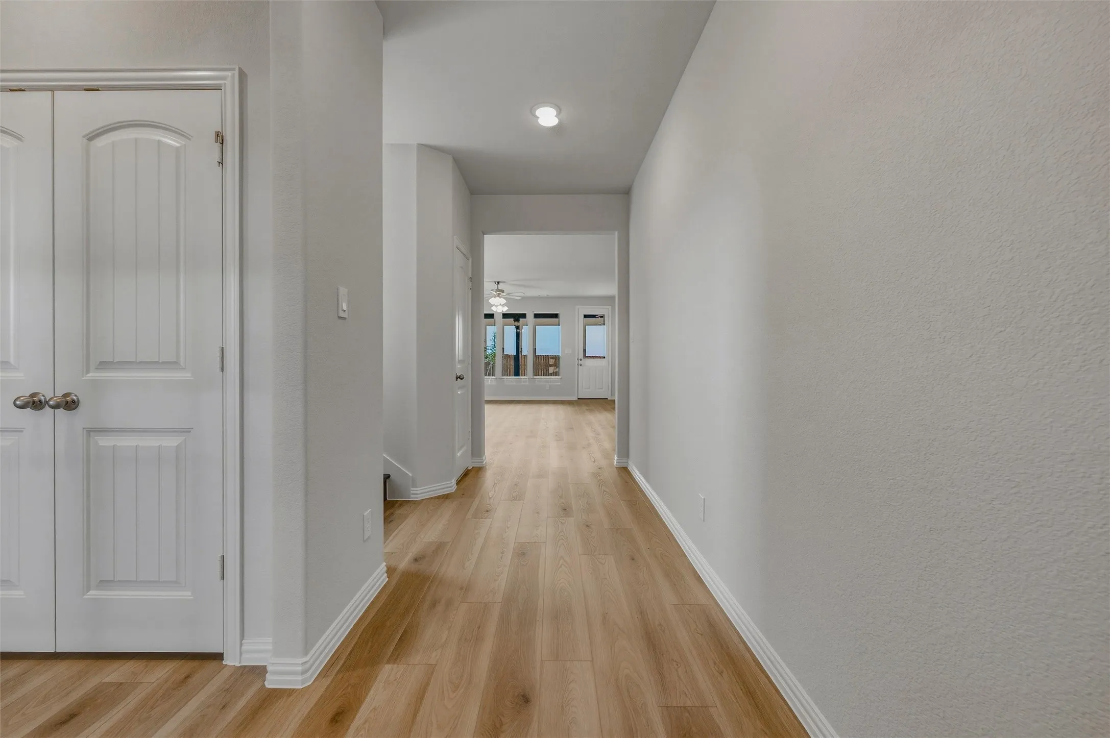 Light wood-finish flooring throughout, white interior doors, recessed ceiling lighting, and crisp white trim