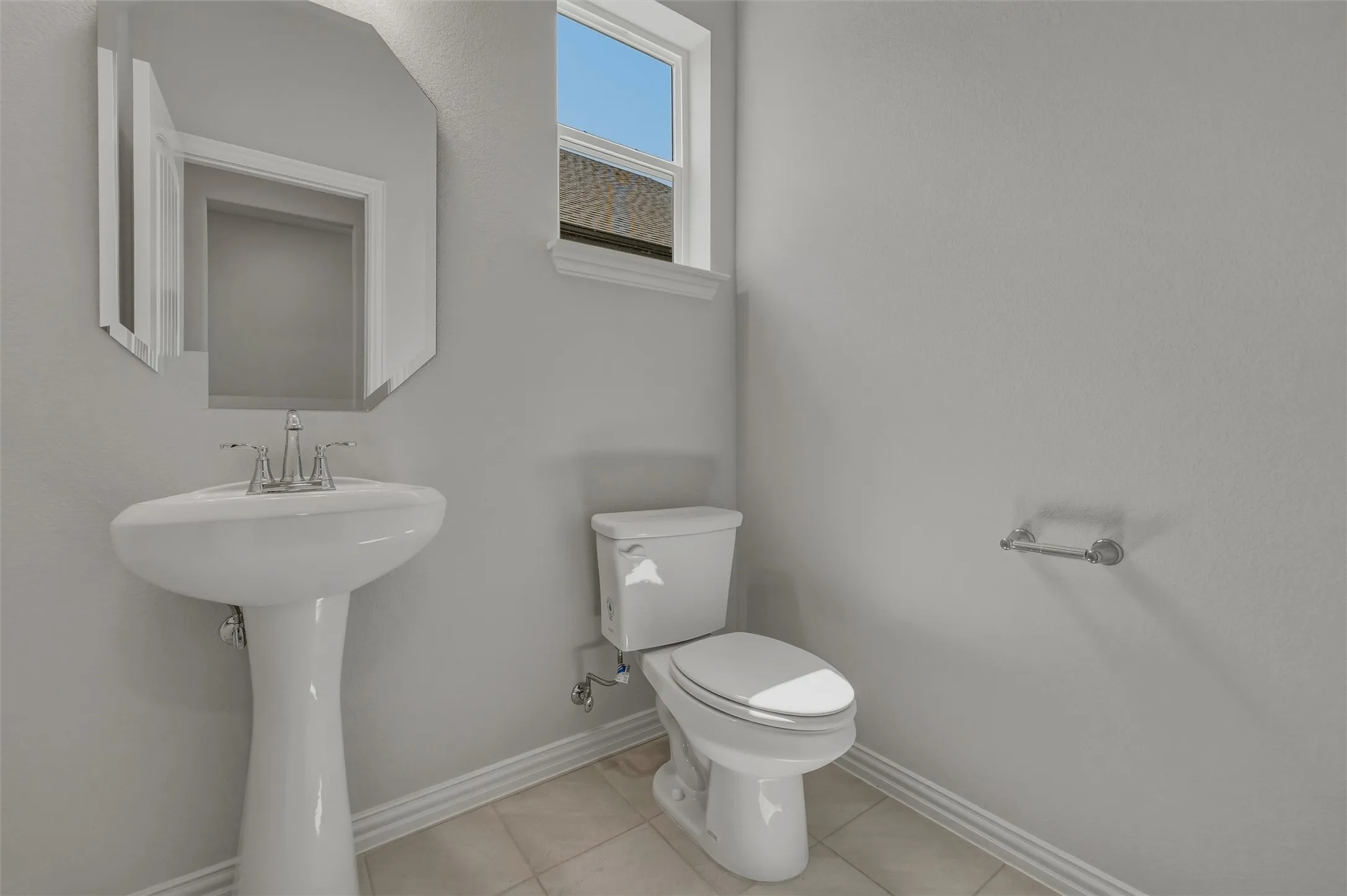 Pedestal sink with chrome faucet, beveled mirror, window with natural light, and tile flooring