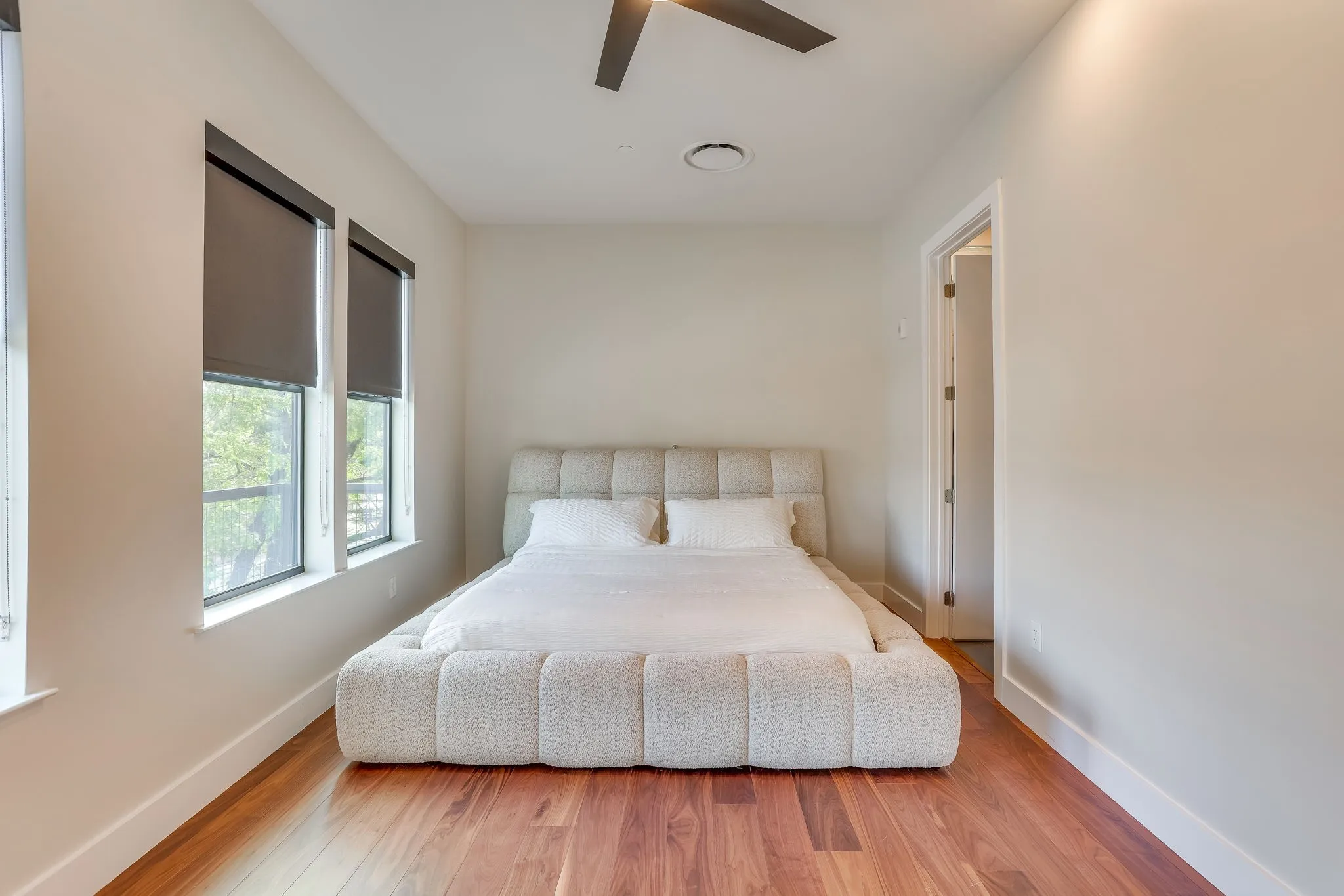 Bedroom featuring Carlisle wide plank hardwood flooring, large windows with roller shades, ceiling fan and recessed lighting