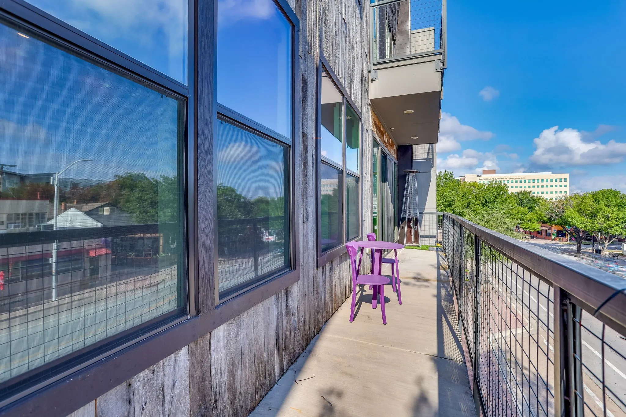 Private Concrete balcony featuring a dark metal grid railing and wood paneled exterior