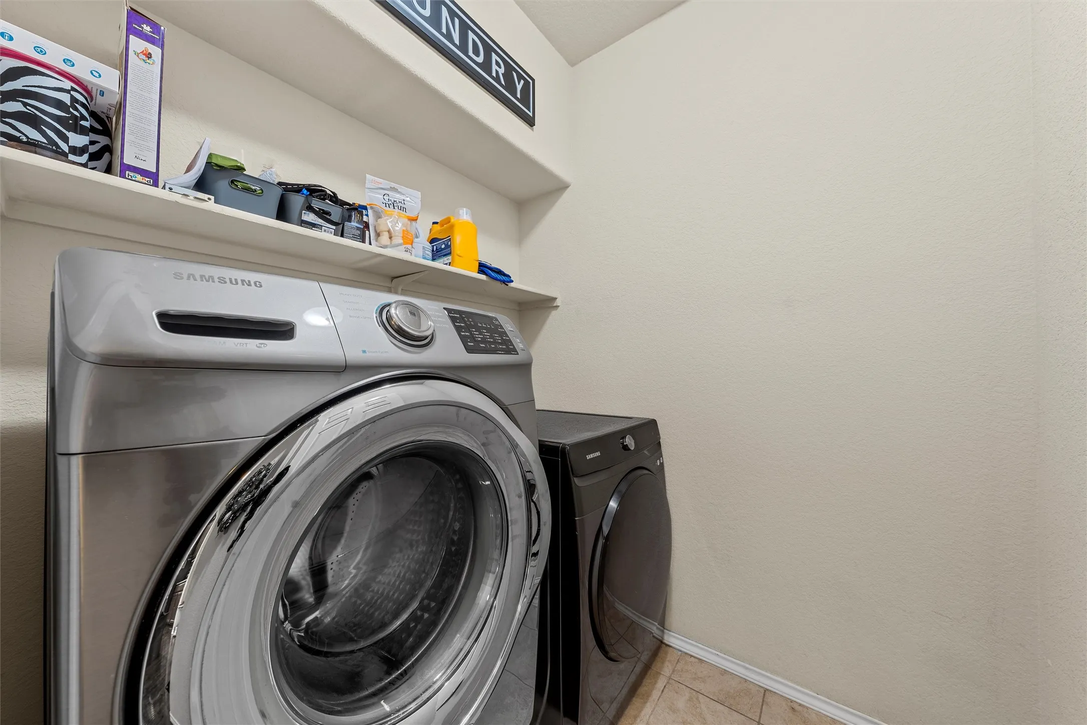 Dedicated utility area featuring a wall-mounted shelf, tiled flooring, and neutral wall tones