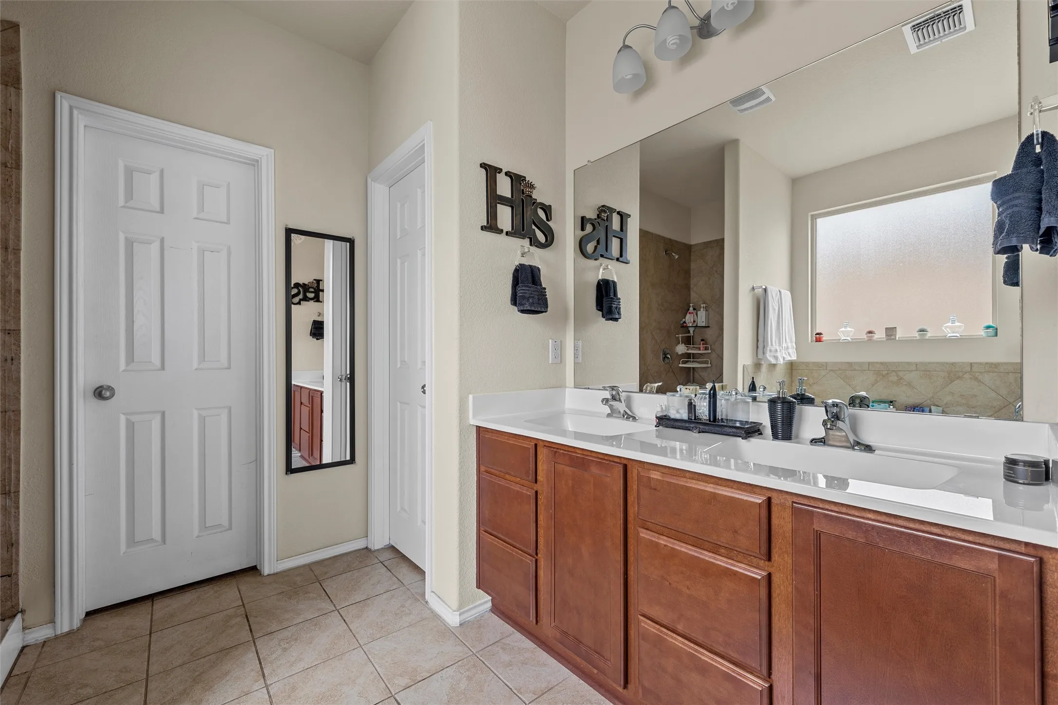 Double vanity with integrated sinks, white countertops, and wood-finish cabinetry