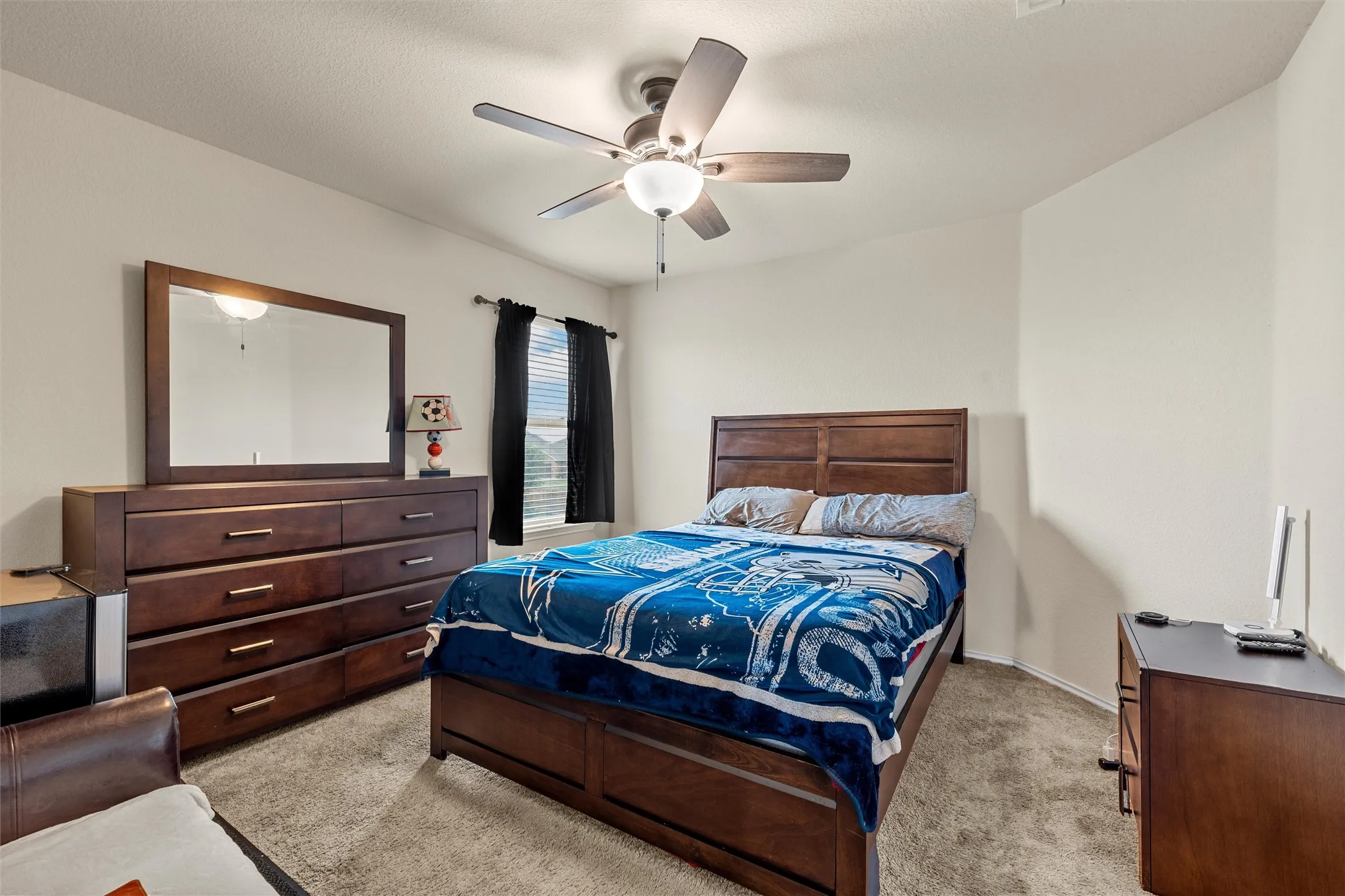 Spacious room featuring neutral carpeting, light-colored walls, and a ceiling fan with integrated lighting