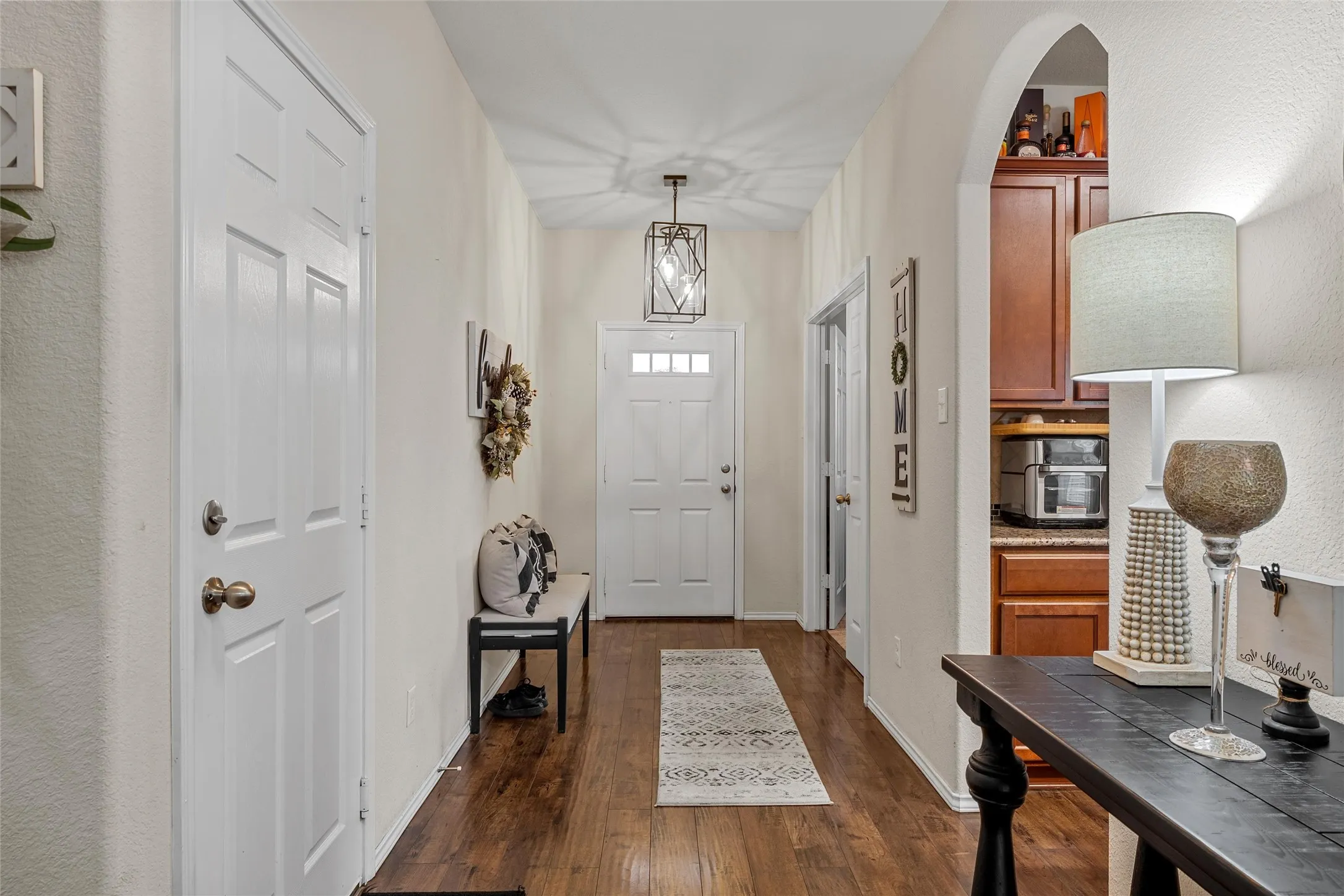 Entryway featuring wood-finish flooring, a contemporary ceiling light fixture, and a white paneled door with glass inserts