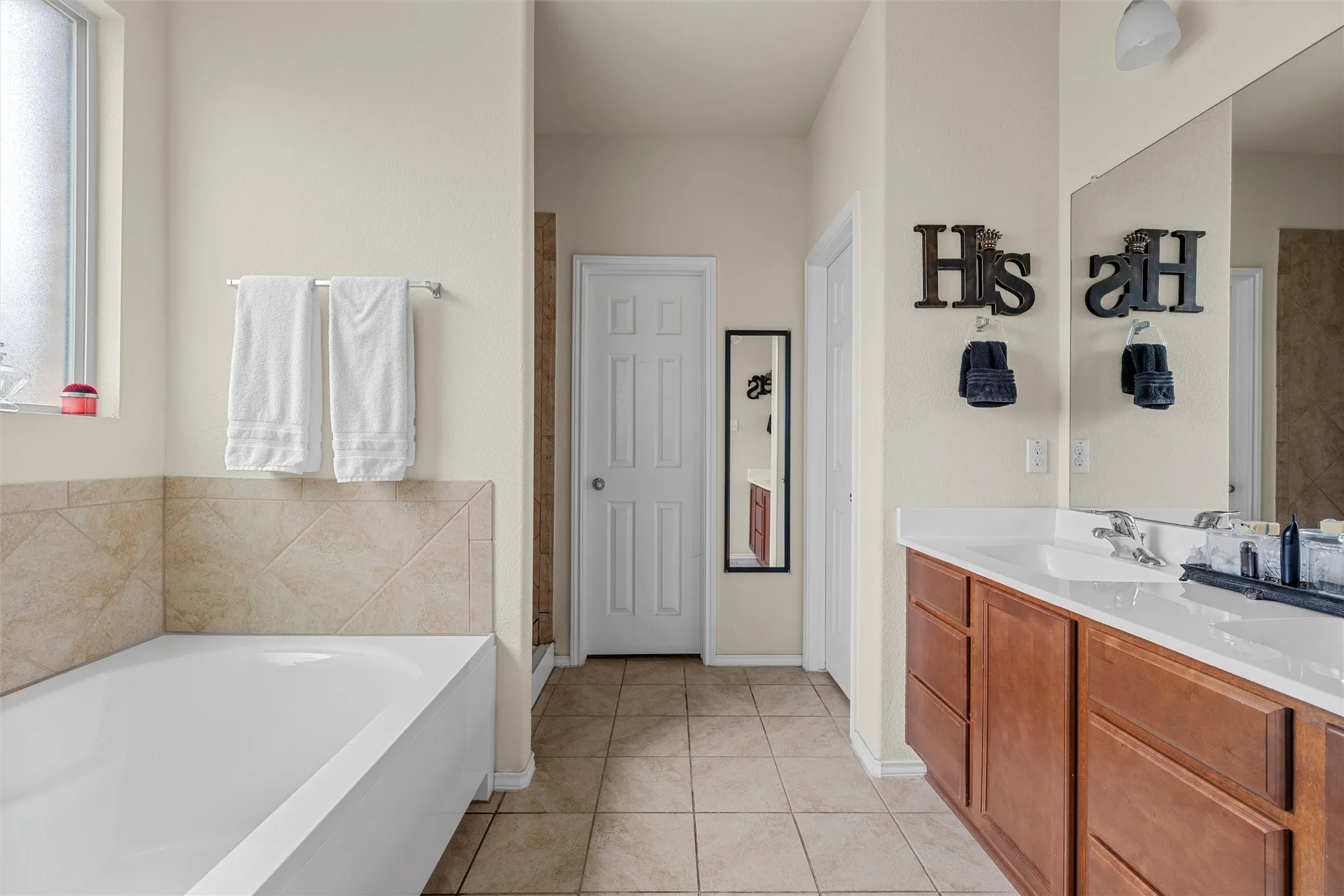 Bathroom featuring a white built-in bathtub with tiled surround, light neutral wall paint, and ceramic tile flooring