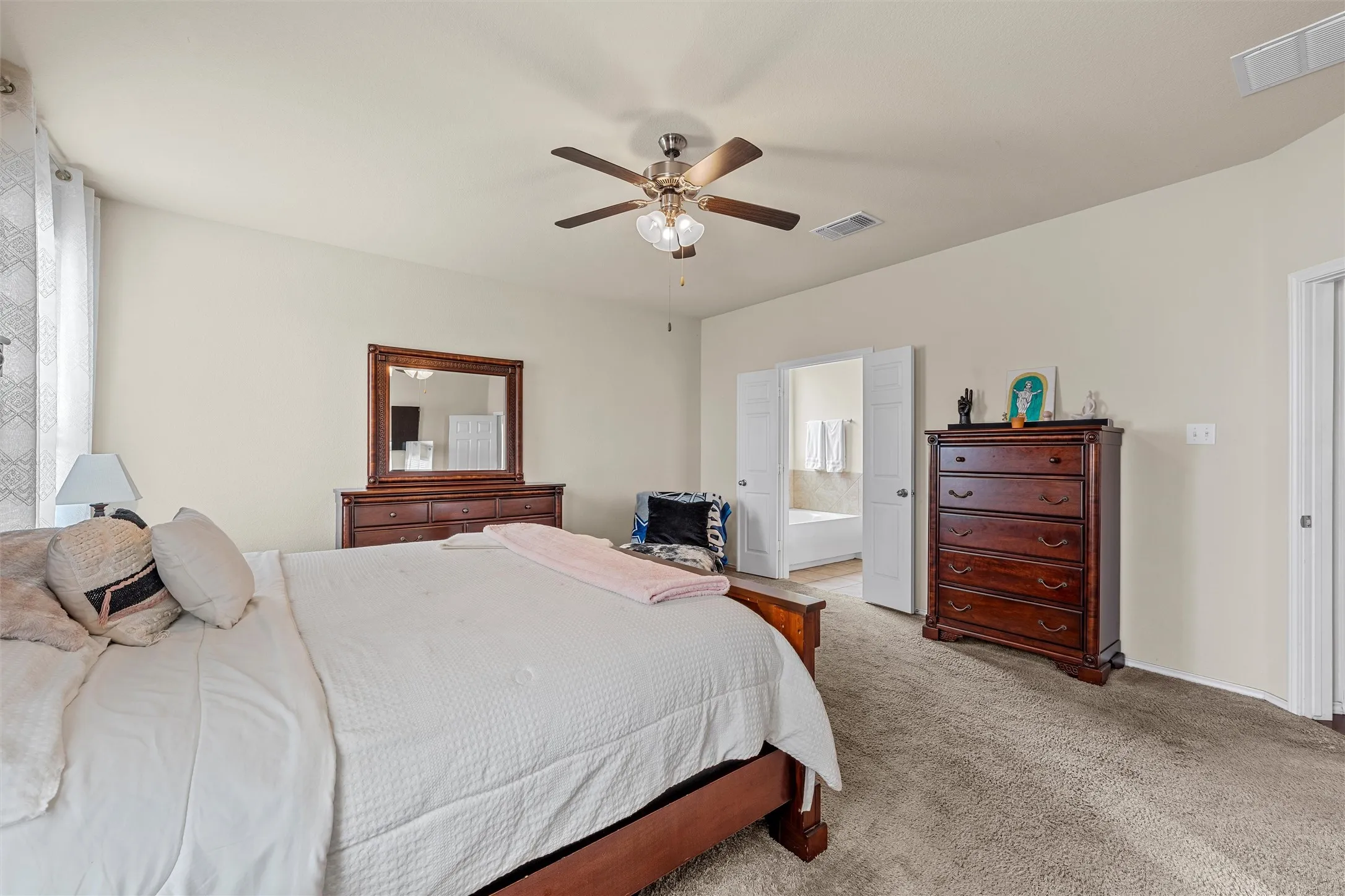 Carpeted bedroom with a ceiling fan light fixture and neutral wall paint