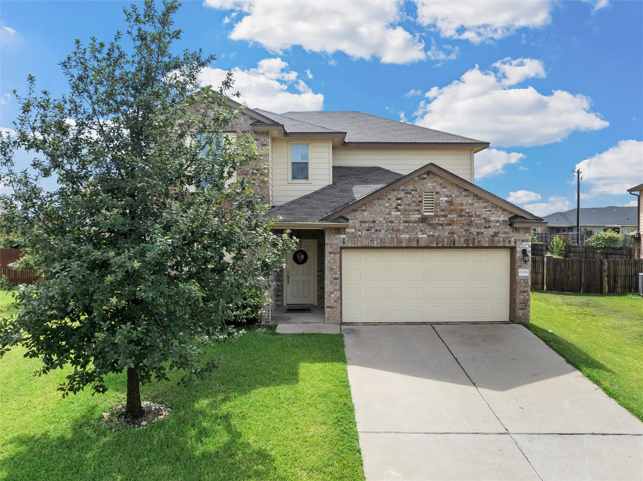 Two-story residence featuring a brick and siding exterior, an attached two-car garage, and a concrete driveway