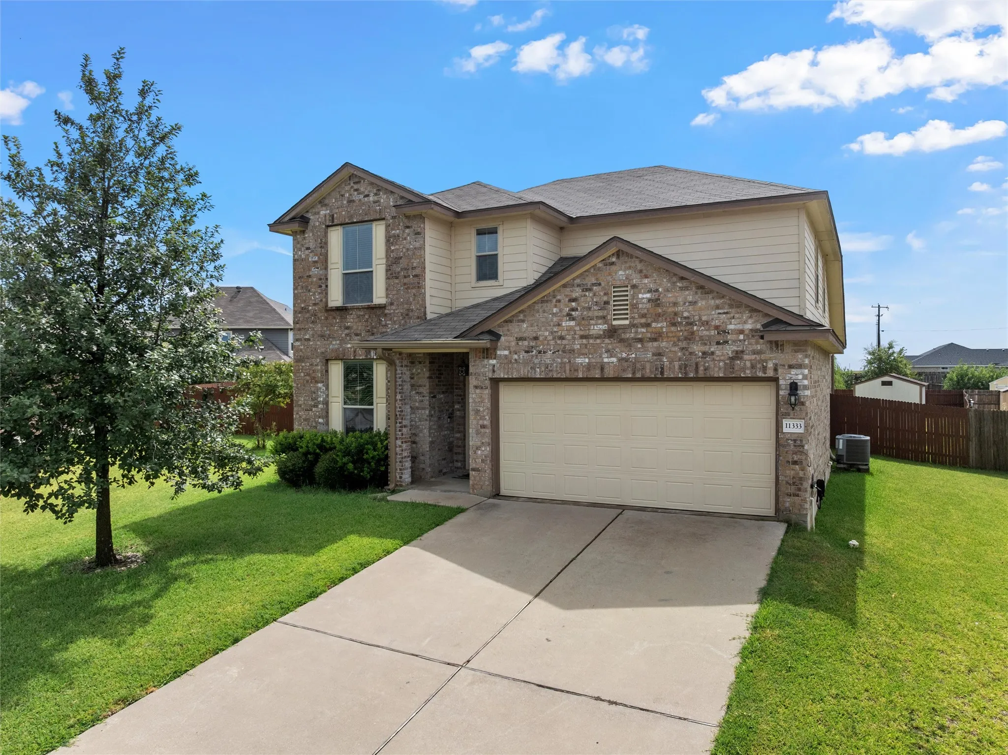 Two-story residence featuring a brick and siding exterior, an attached two-car garage, and a concrete driveway