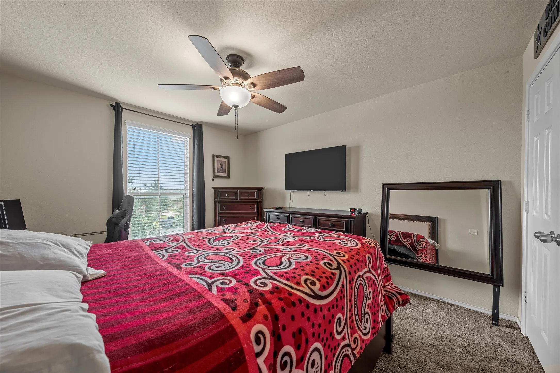 Bedroom featuring a multi-speed ceiling fan with integrated lighting, a large window with blinds, and neutral wall tones