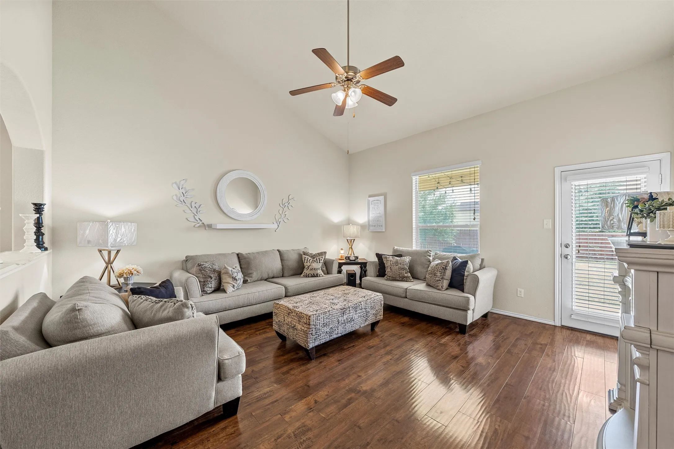 Spacious living area featuring high vaulted ceilings, rich wood-finish flooring, and a ceiling fan with integrated lighting