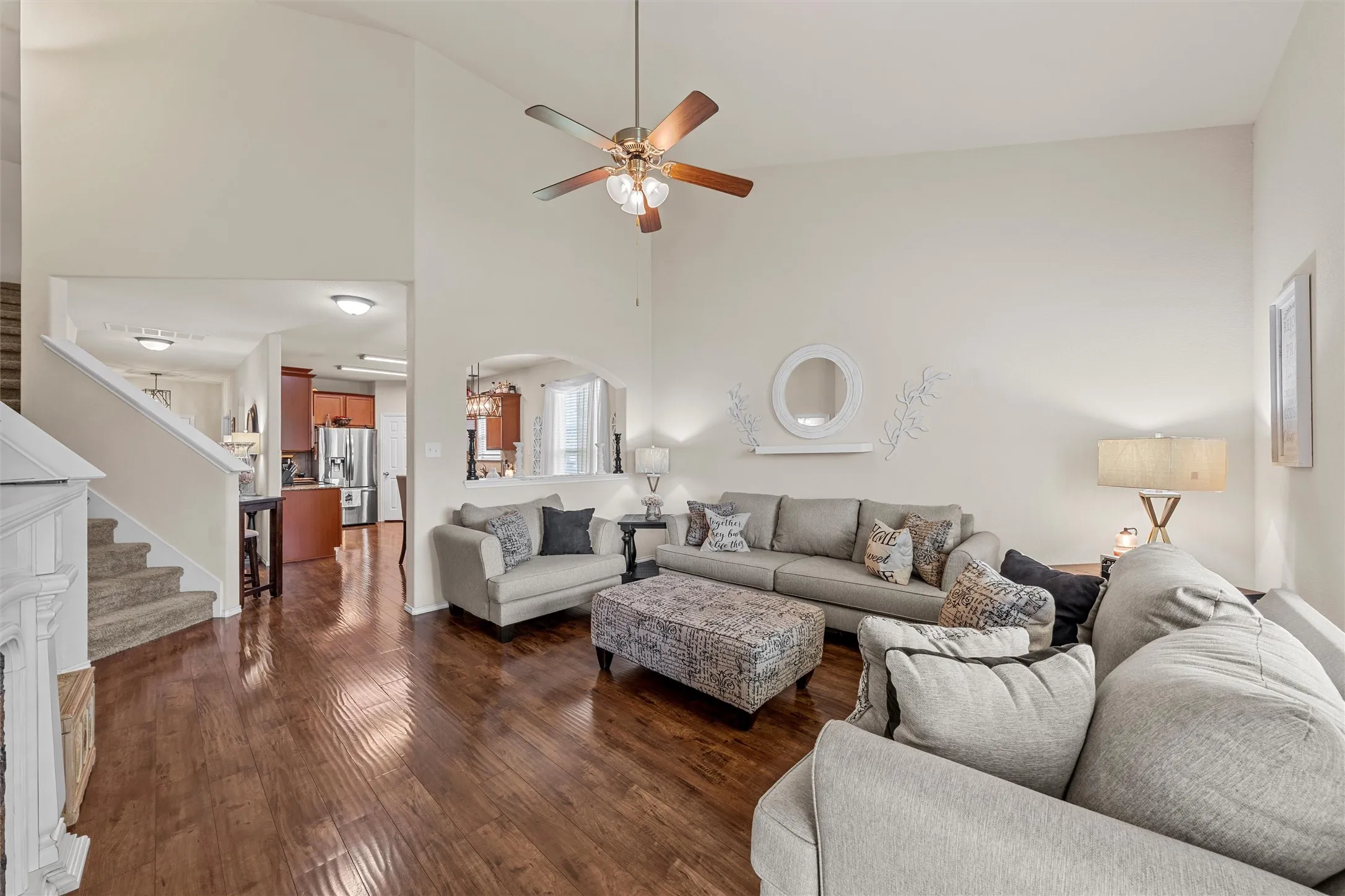 Living space featuring wood-finish flooring, high ceilings, a ceiling fan, and an arched pass-through to the kitchen