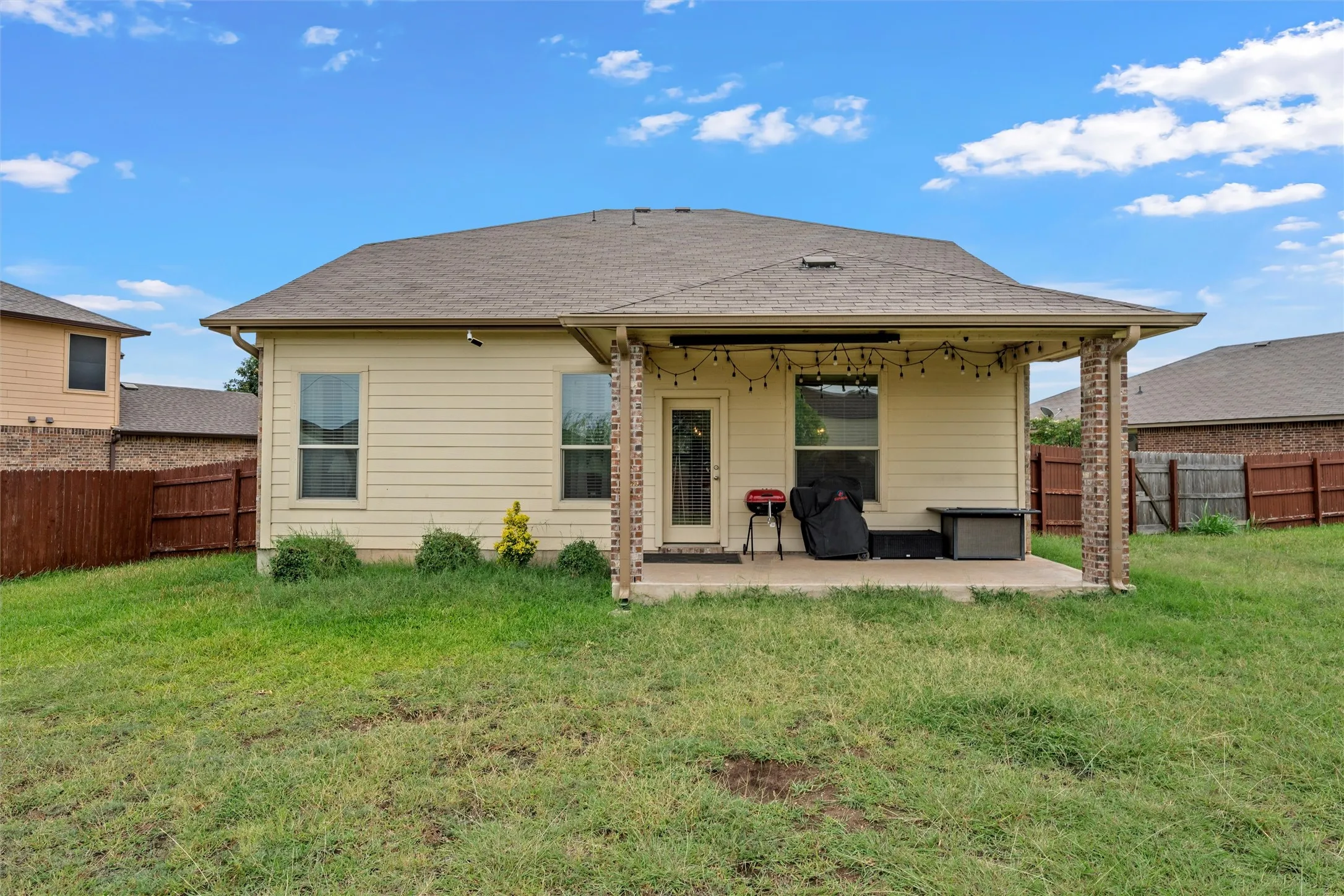Expansive backyard featuring a covered patio, brick columns, and a solid wood privacy fence
