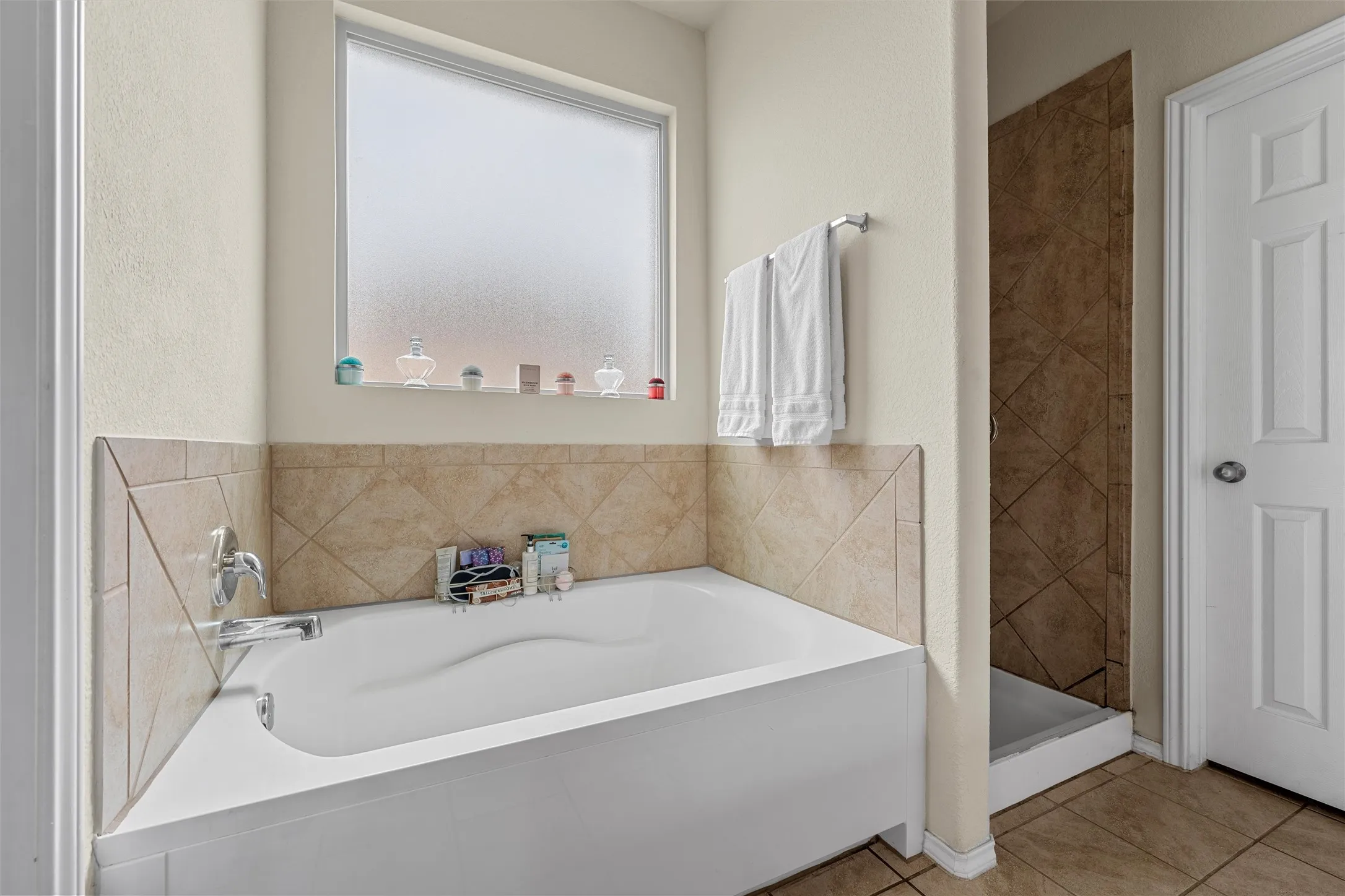 Bathroom featuring a built-in soaking tub with a deck-mounted faucet, complemented by a tiled surround