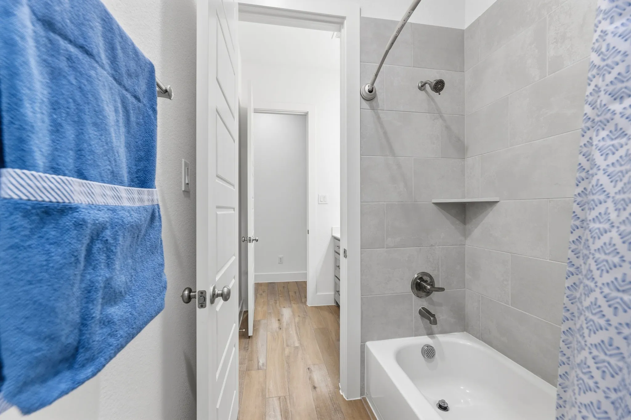 Bathtub with light gray subway tile surround and integrated corner shelf