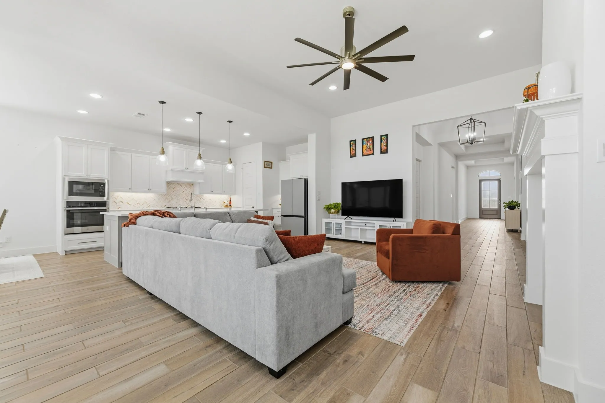 Open-concept living area featuring wood-finish flooring, a contemporary ceiling fan, and recessed lighting