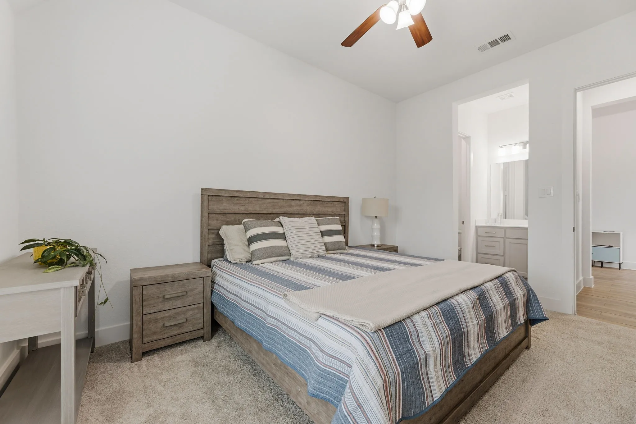 Carpeted bedroom with a wood-finish bed frame and ceiling fan