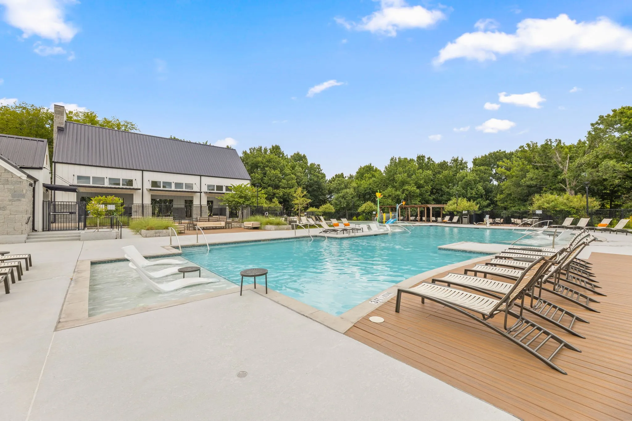 Expansive outdoor swimming pool with integrated tanning ledge and surrounding concrete deck
