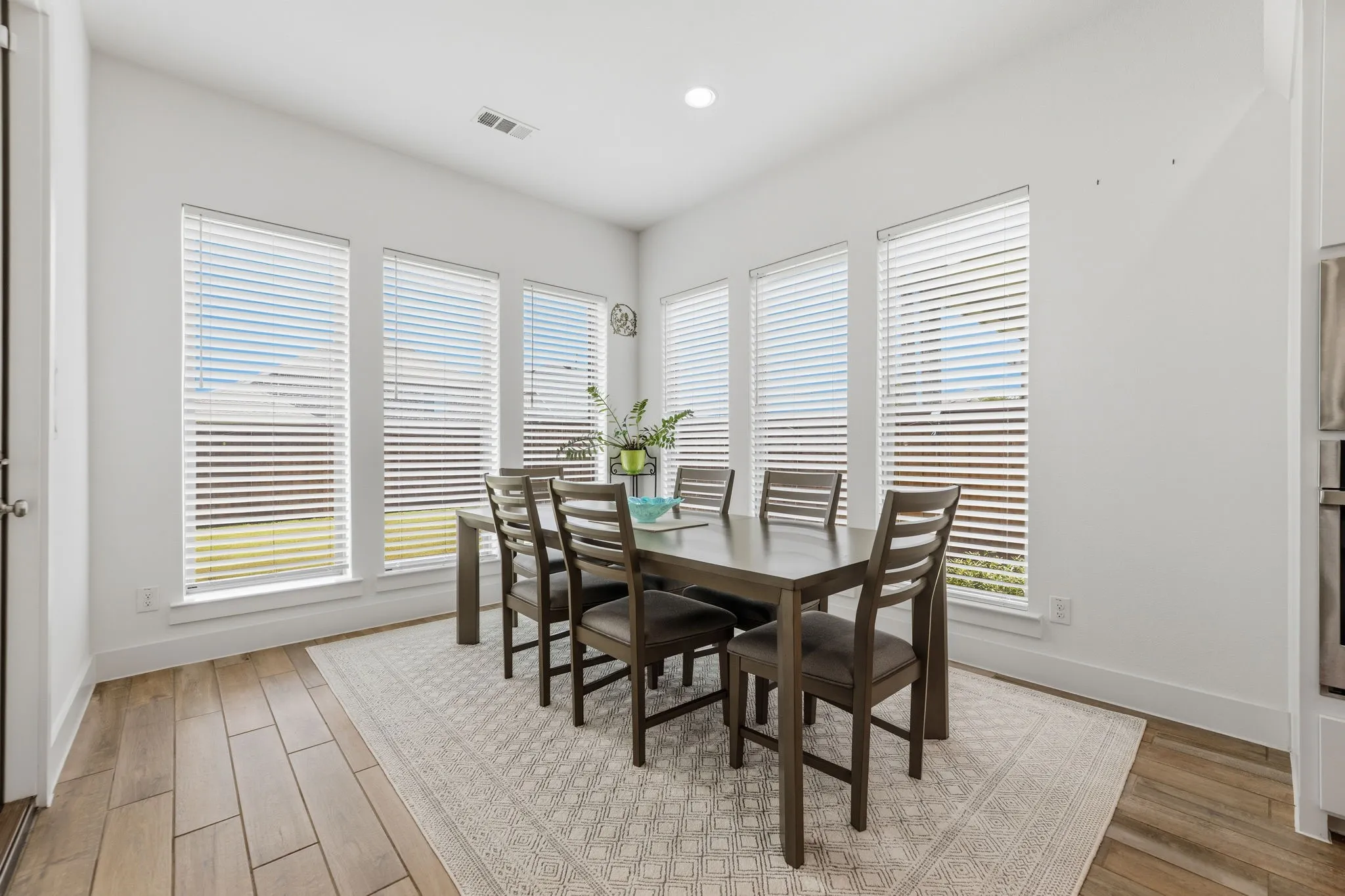 Dining area featuring wood-finish flooring and three large windows