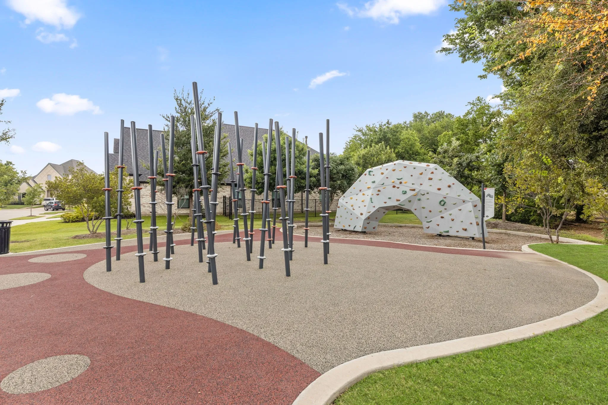 Community park featuring modern climbing structures, a bouldering wall, and soft-fall surfacing