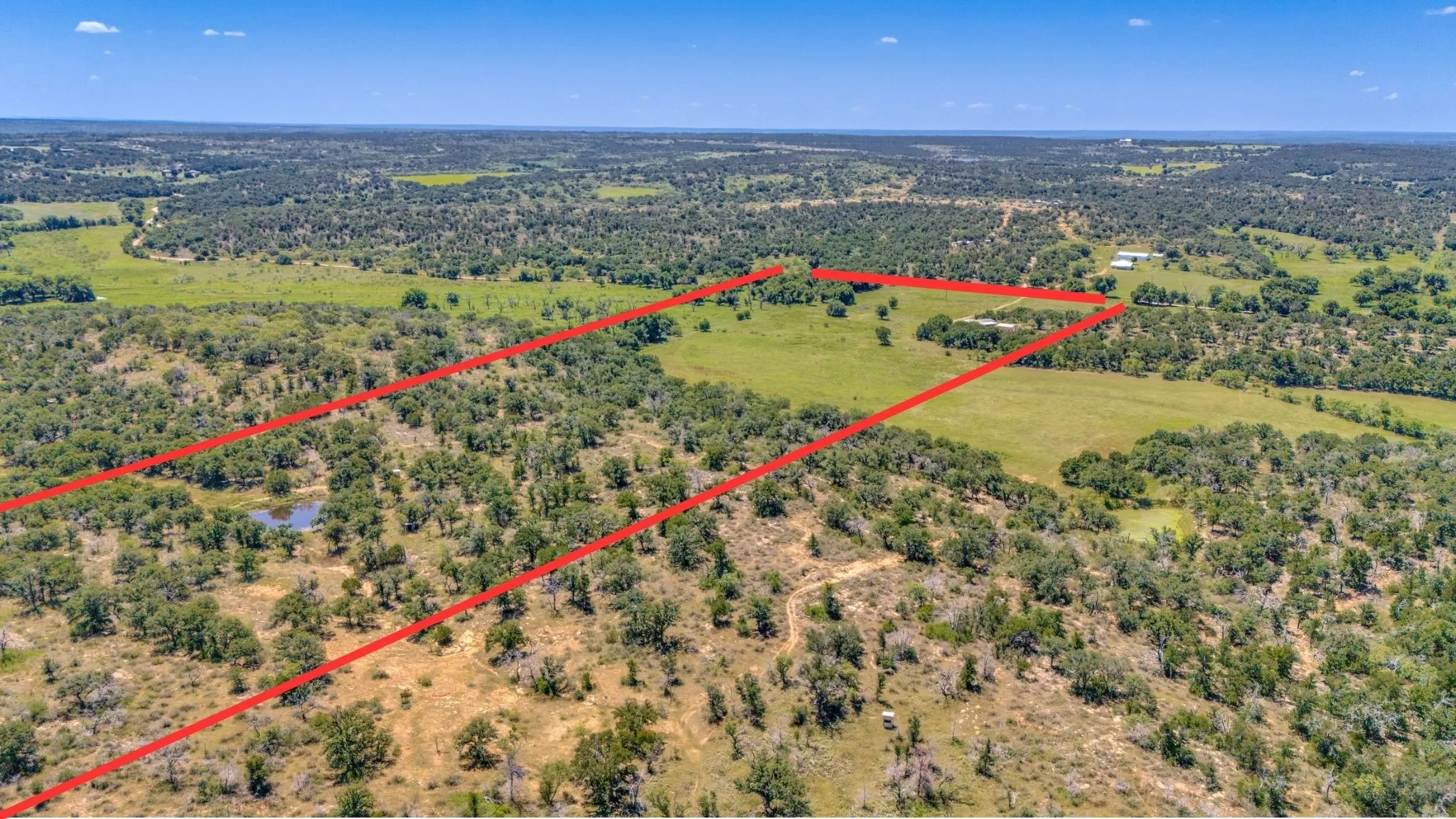 Expansive acreage featuring a natural pond, scattered trees, and open grassy areas