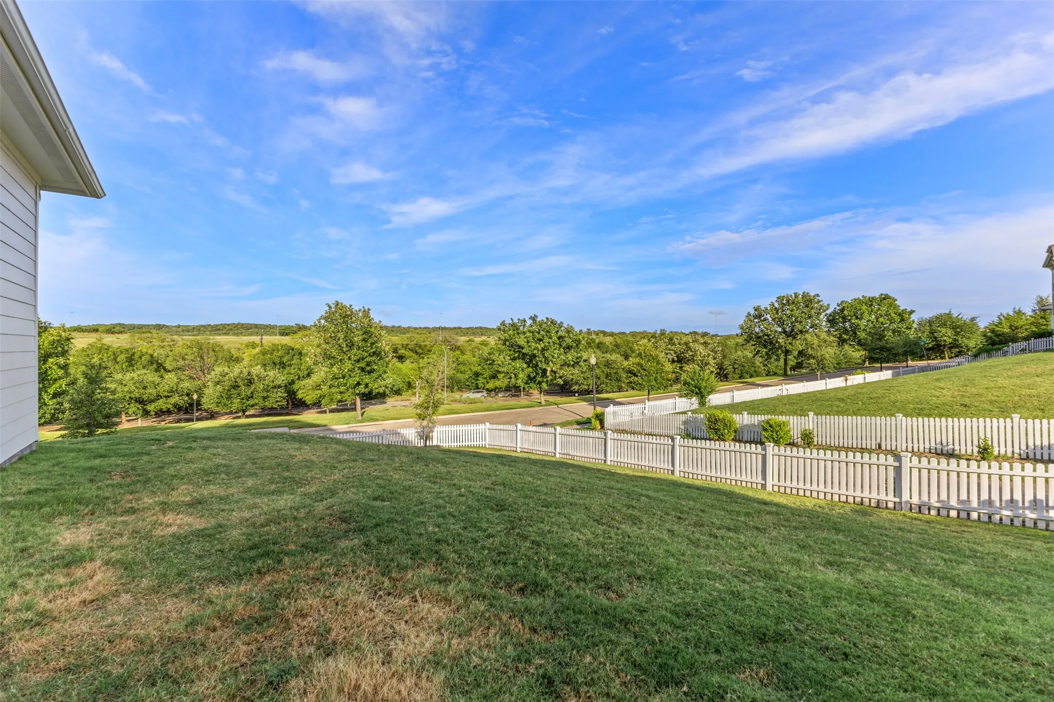Expansive green lawn with a white picket fence bordering the property