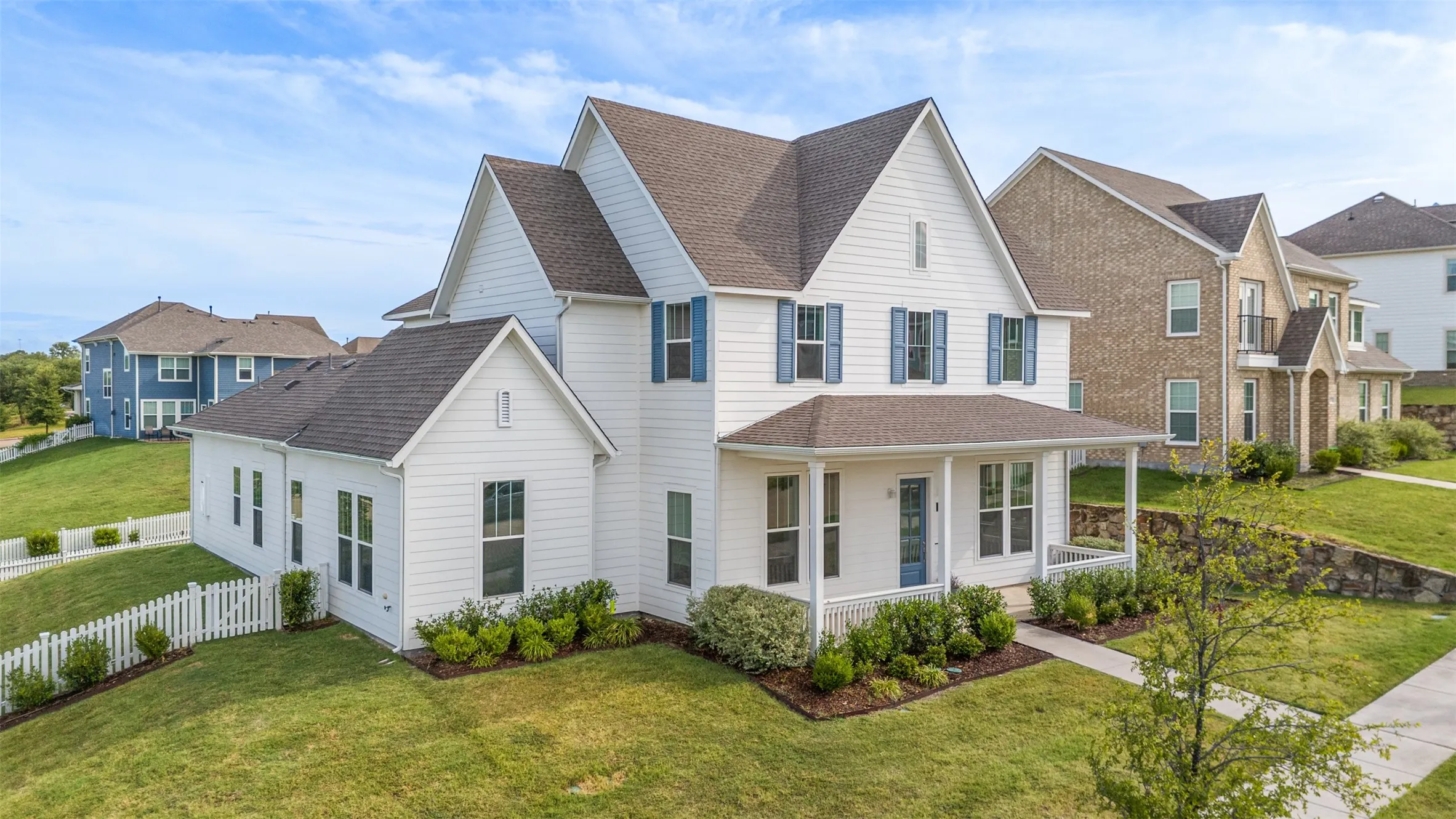 Two-story residence featuring white siding, a covered front porch with white columns, and blue window shutters