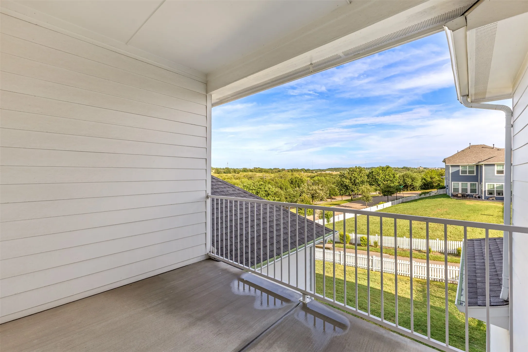 Covered balcony featuring concrete flooring and white metal railings