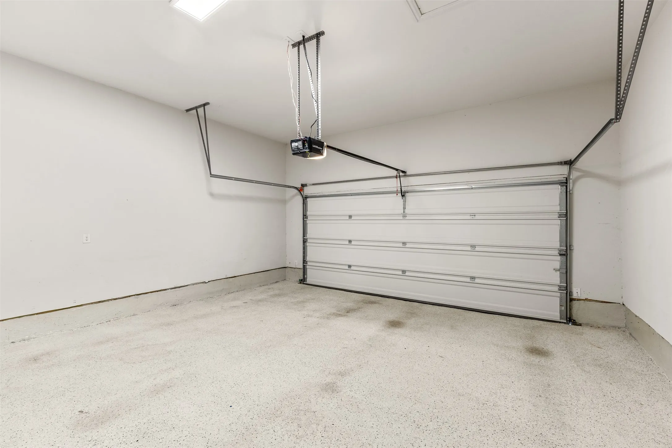 Spacious garage featuring an automatic sectional door, an epoxy-coated concrete floor, and overhead lighting