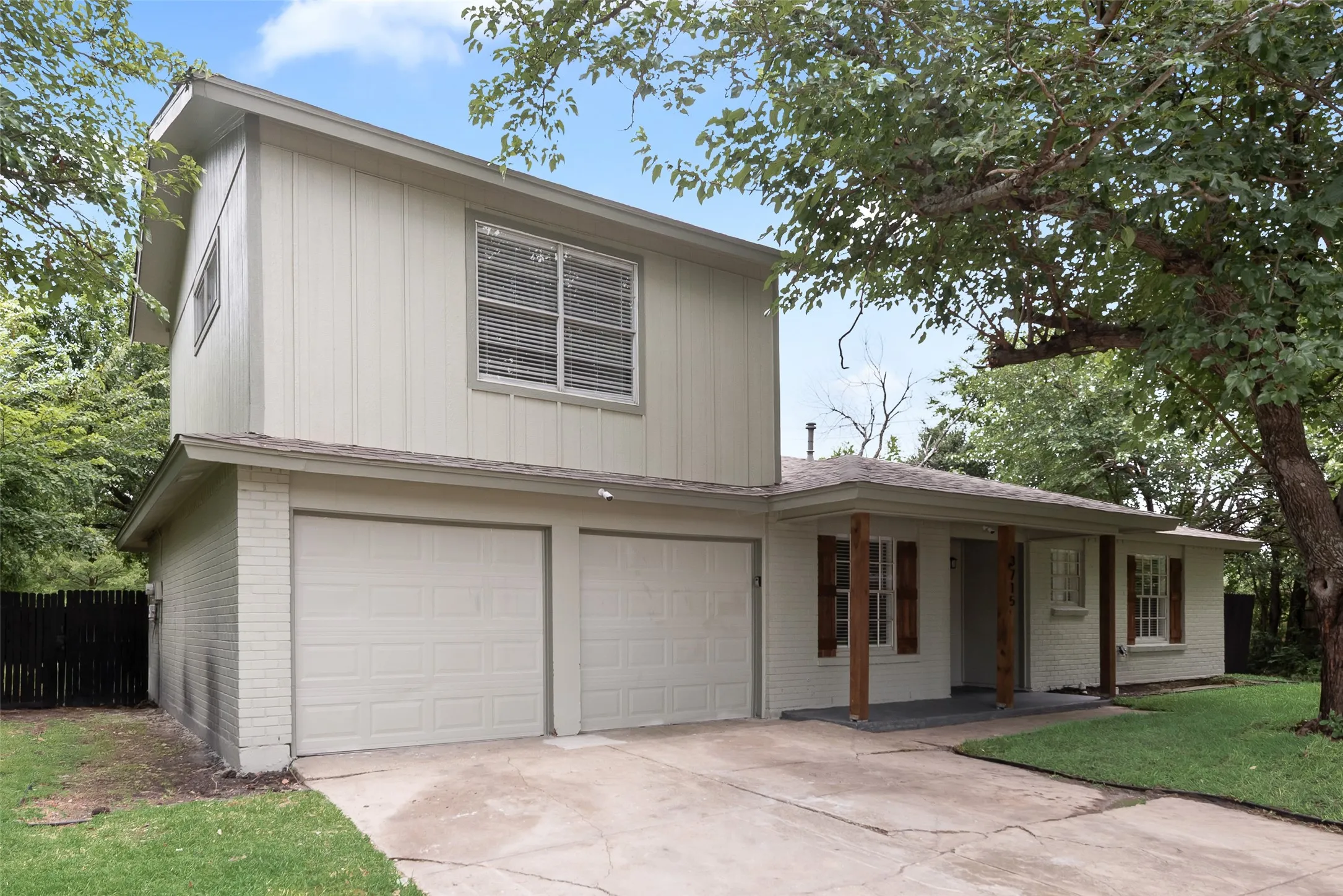 Two-story residence featuring a two-car garage, light-colored exterior siding, and brick accents