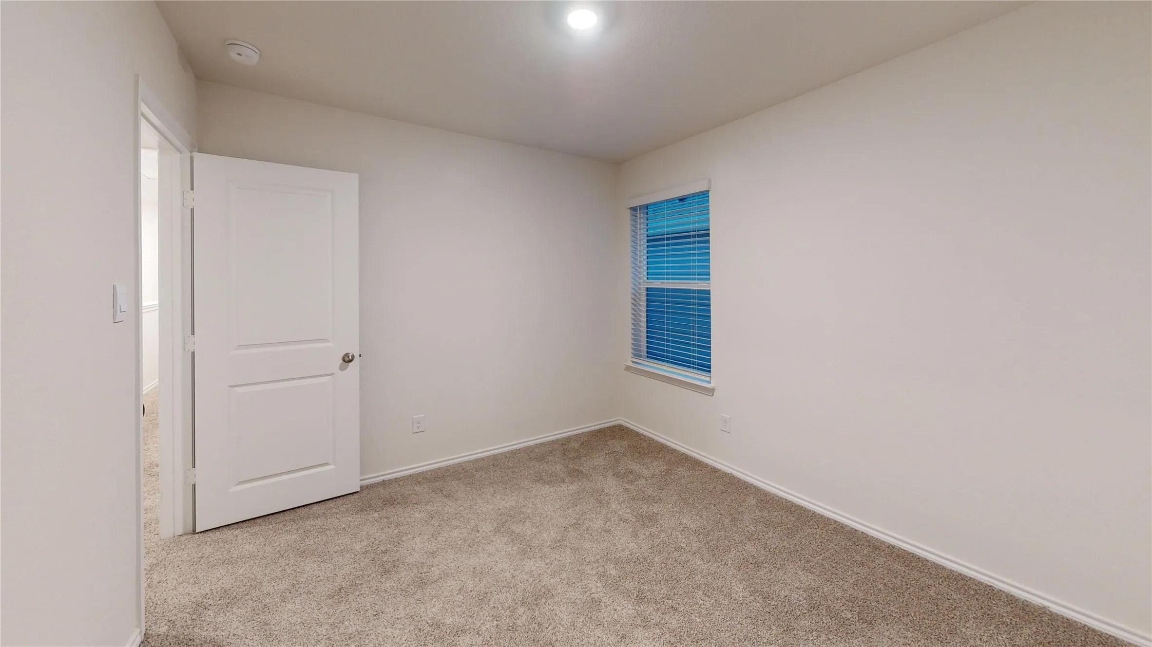 Neutral tone wall paint, light brown carpet flooring, and a two-panel interior door with a silver knob