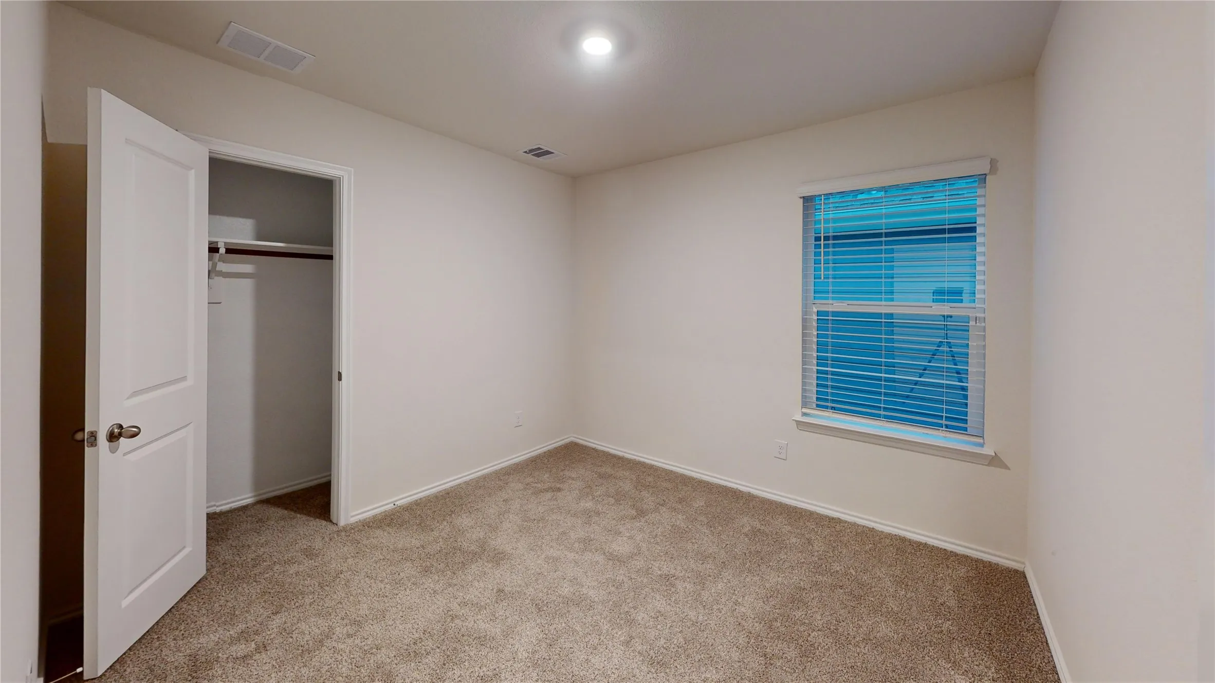 Room featuring neutral carpeting, white painted walls, a single window with blinds, and a closet with an open door