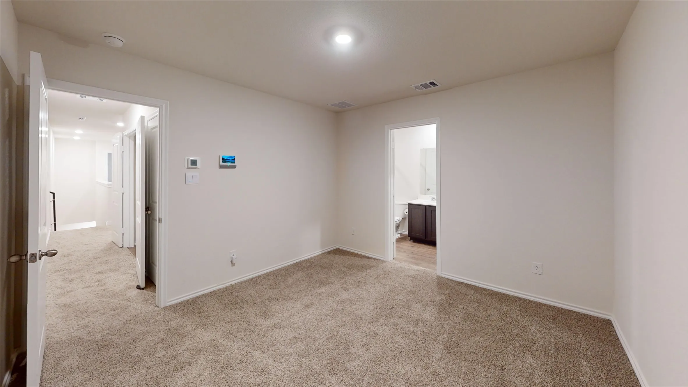 Carpeted room with recessed lighting and a digital thermostat