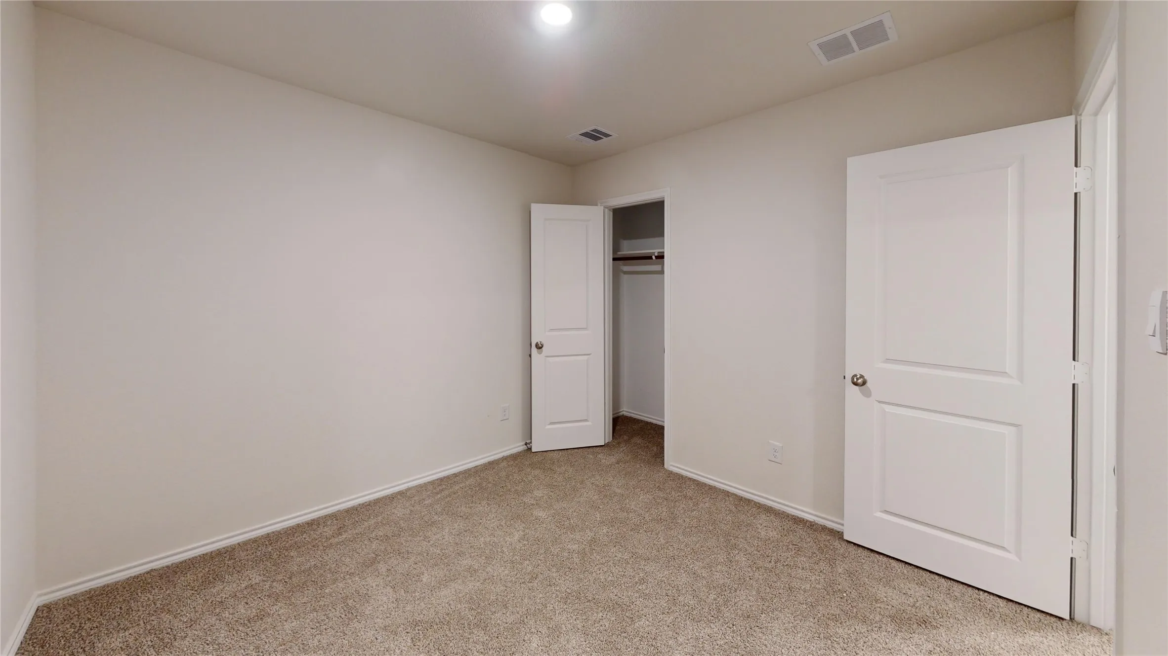 Spacious room featuring neutral carpeting, light-toned walls, and white trim