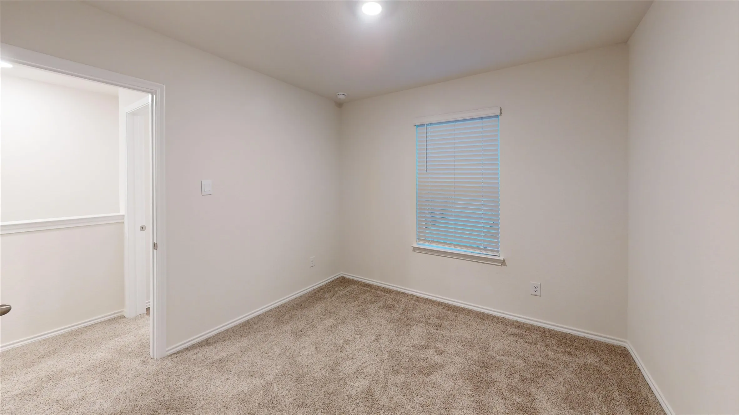 Carpeted interior room featuring a single window with blinds and neutral-toned walls