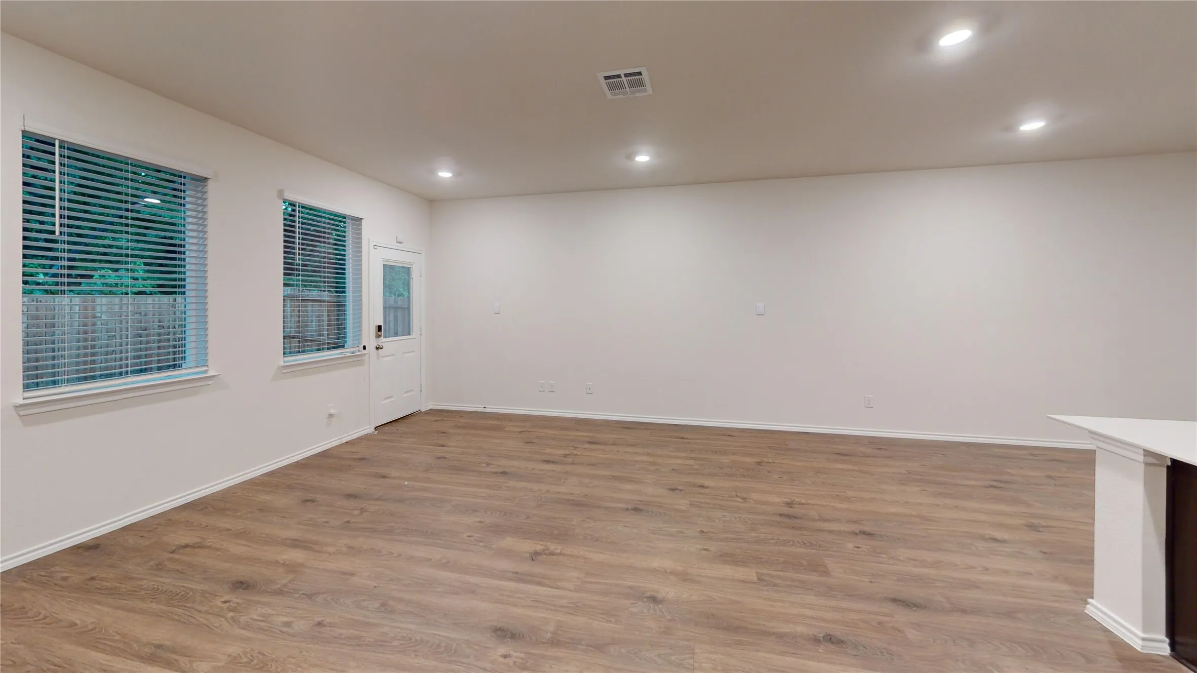 Spacious interior featuring wood-finish flooring, recessed lighting, and bright white walls