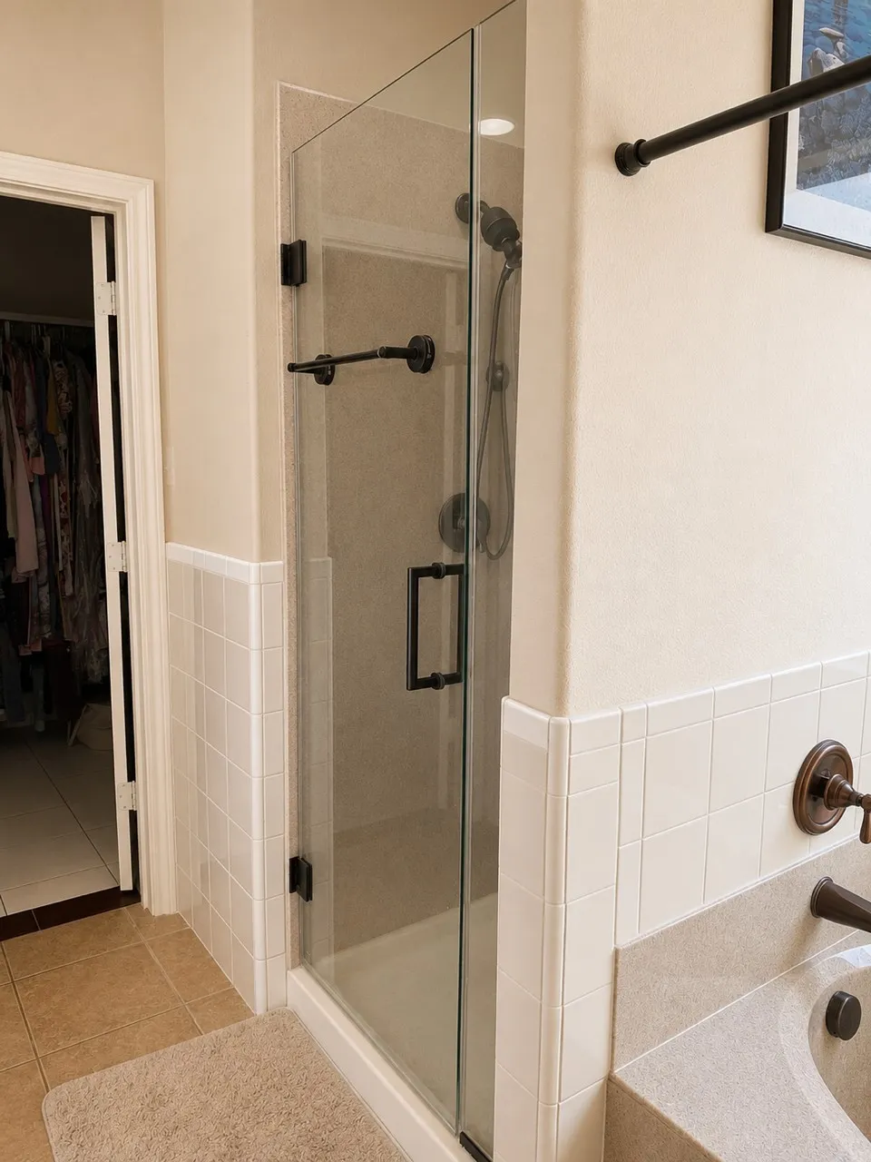 Enclosed glass shower with matte black fixtures and a built-in shower head