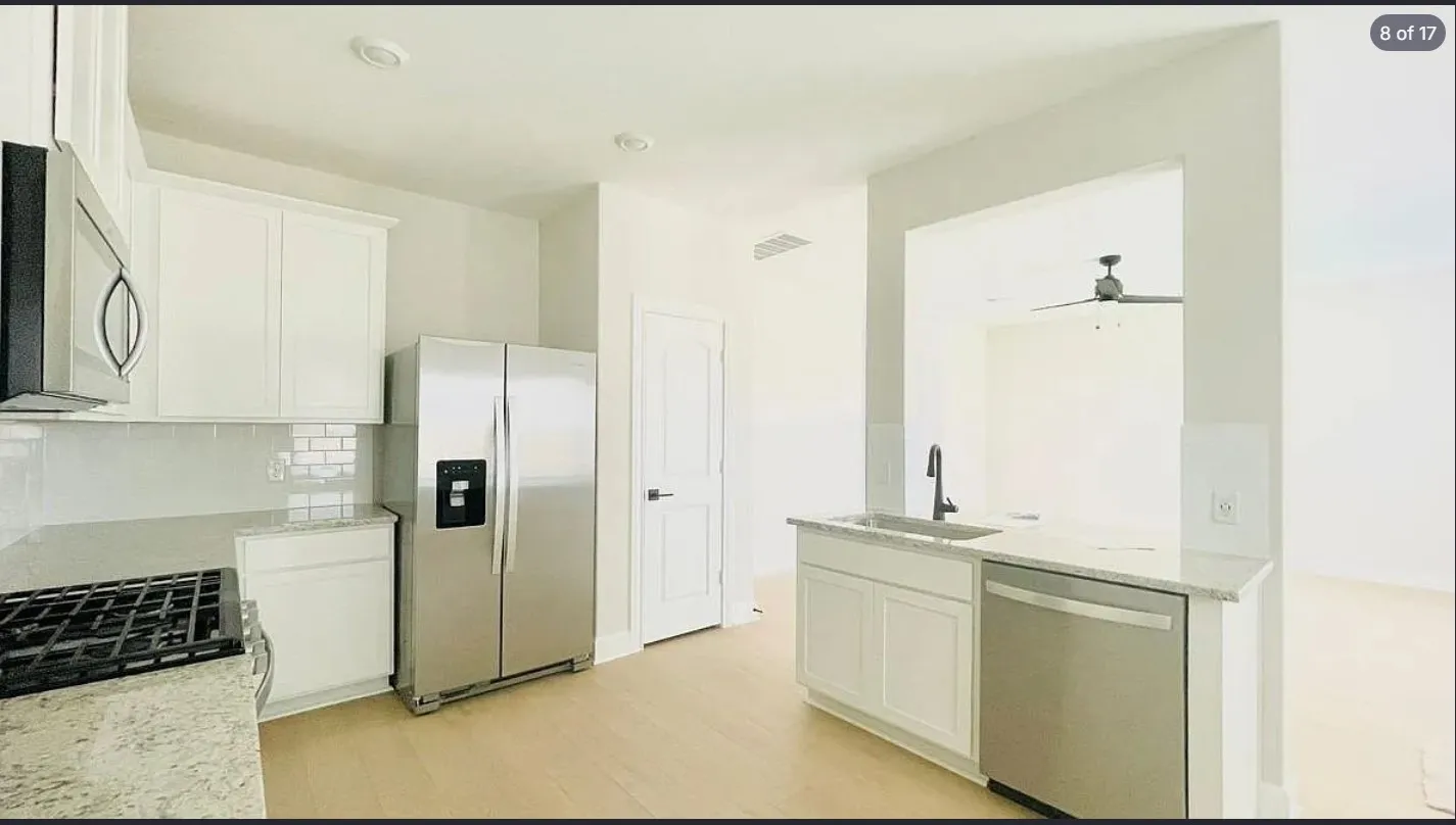 Modern kitchen featuring light wood-finish flooring, white cabinetry, and light-toned countertops