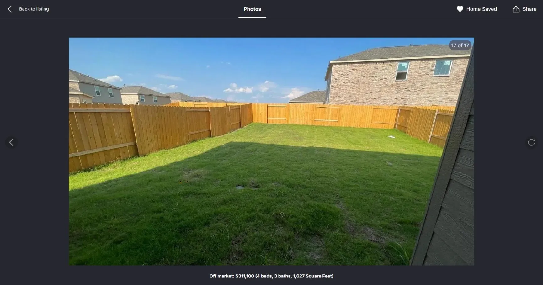 Expansive backyard featuring a manicured lawn, full wood privacy fence, and partial brick exterior of the residence