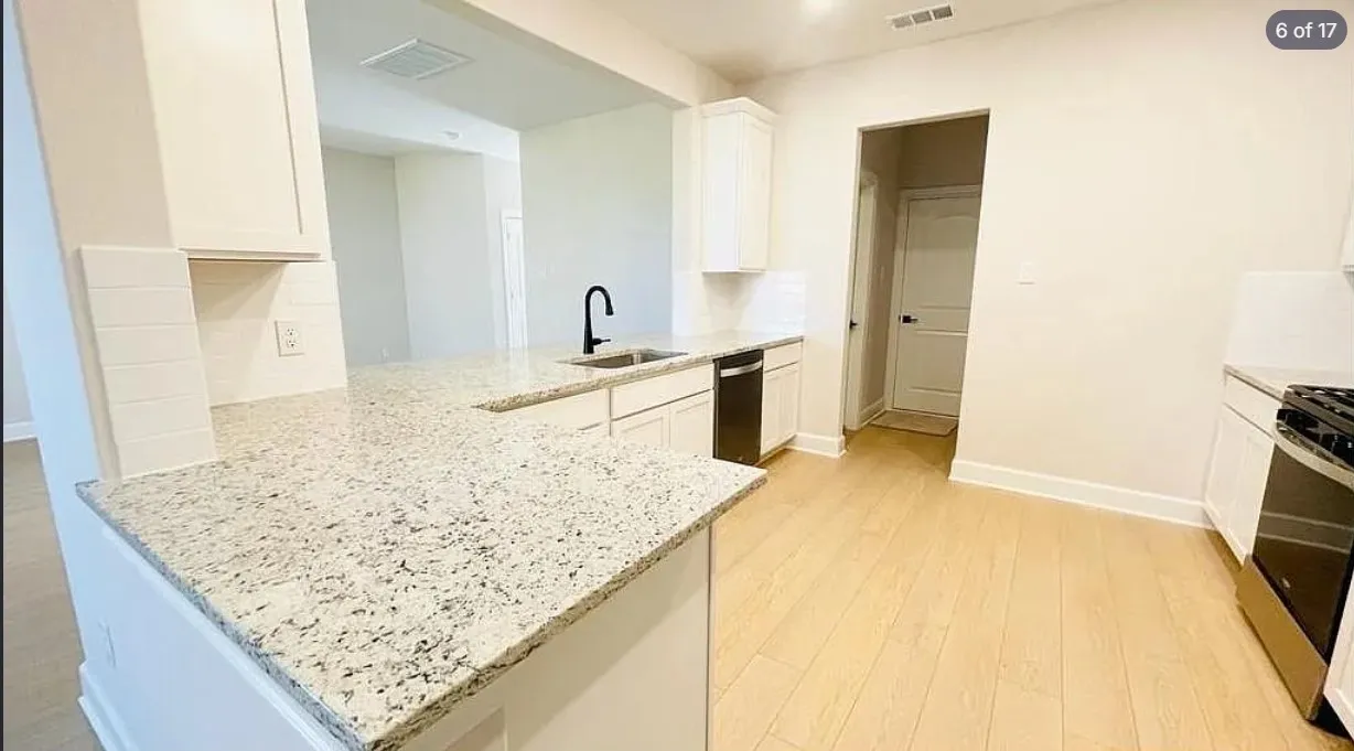 Kitchen featuring light wood-finish flooring, white cabinetry, speckled countertops, stainless steel appliances, and a subway tile backsplash