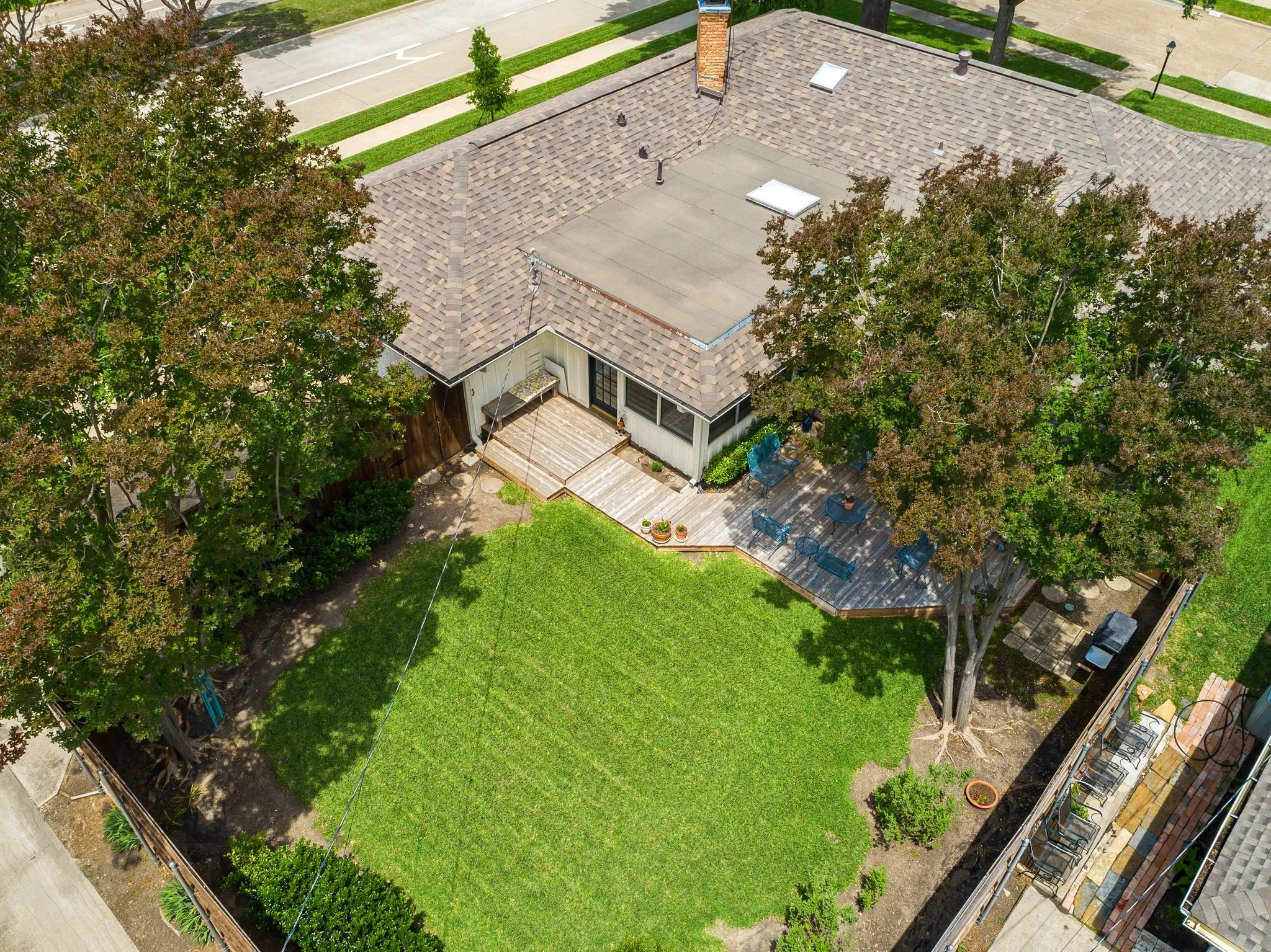 Expansive backyard featuring a manicured lawn, a multi-level wood deck, and mature trees