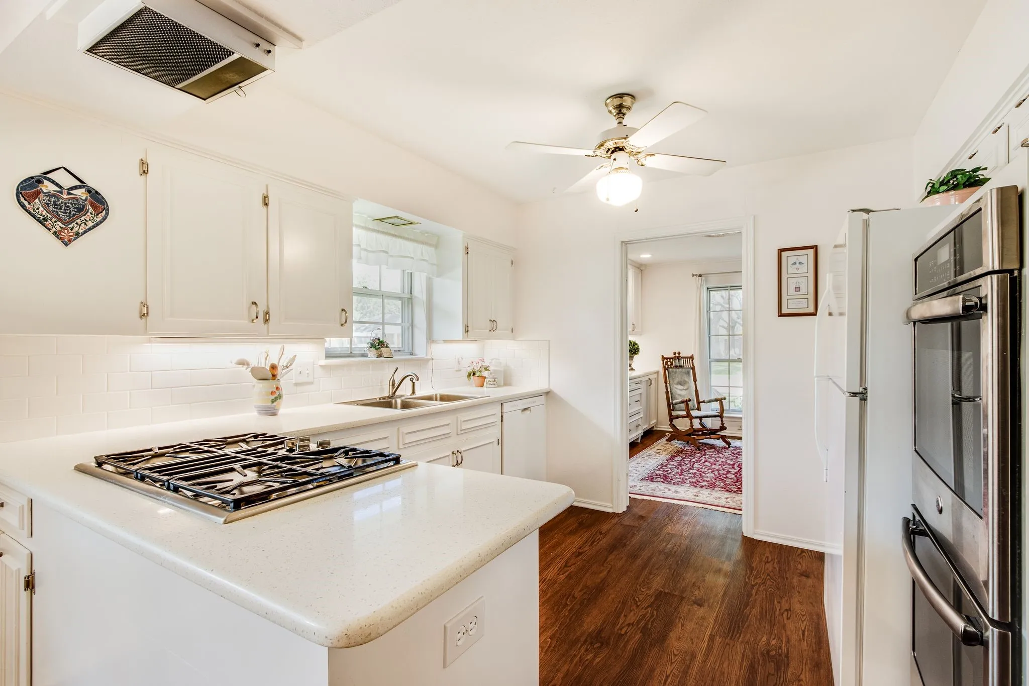 Kitchen featuring white cabinetry, light-toned countertops, a built-in cooktop, and wood-finish flooring