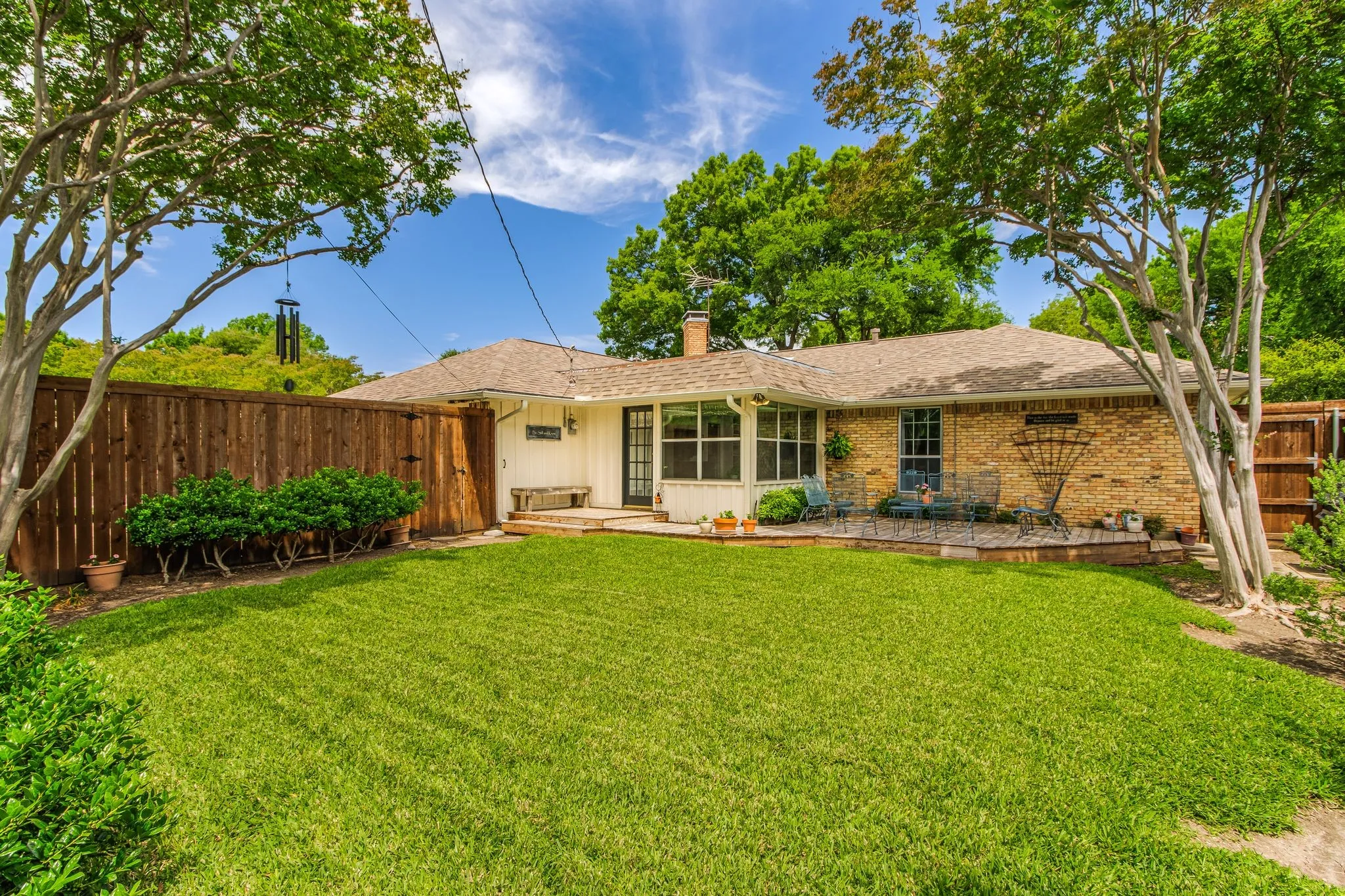 Expansive green lawn with mature trees and a wood privacy fence