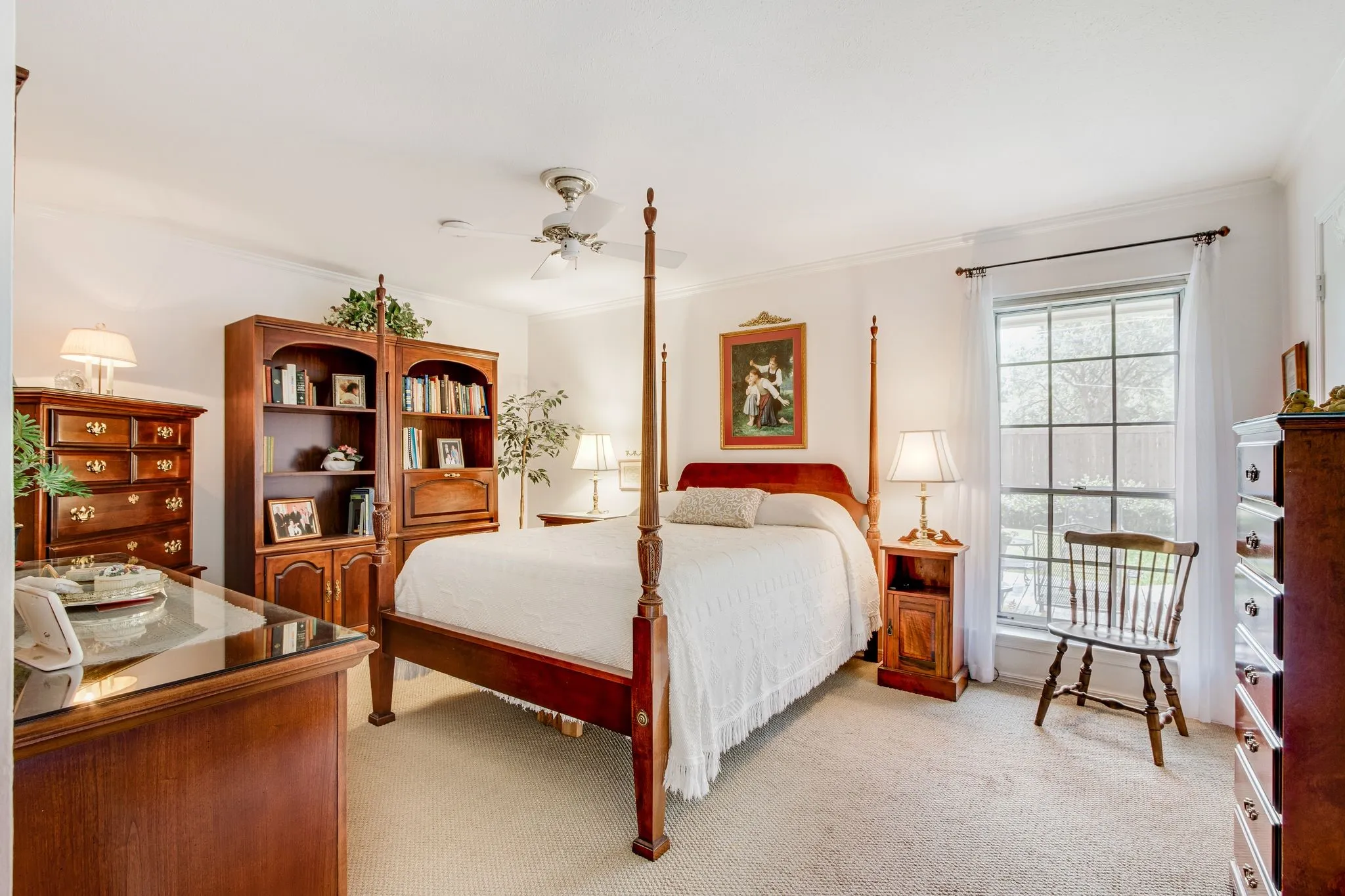 Light-filled room featuring neutral carpet, crown molding, and a ceiling fan