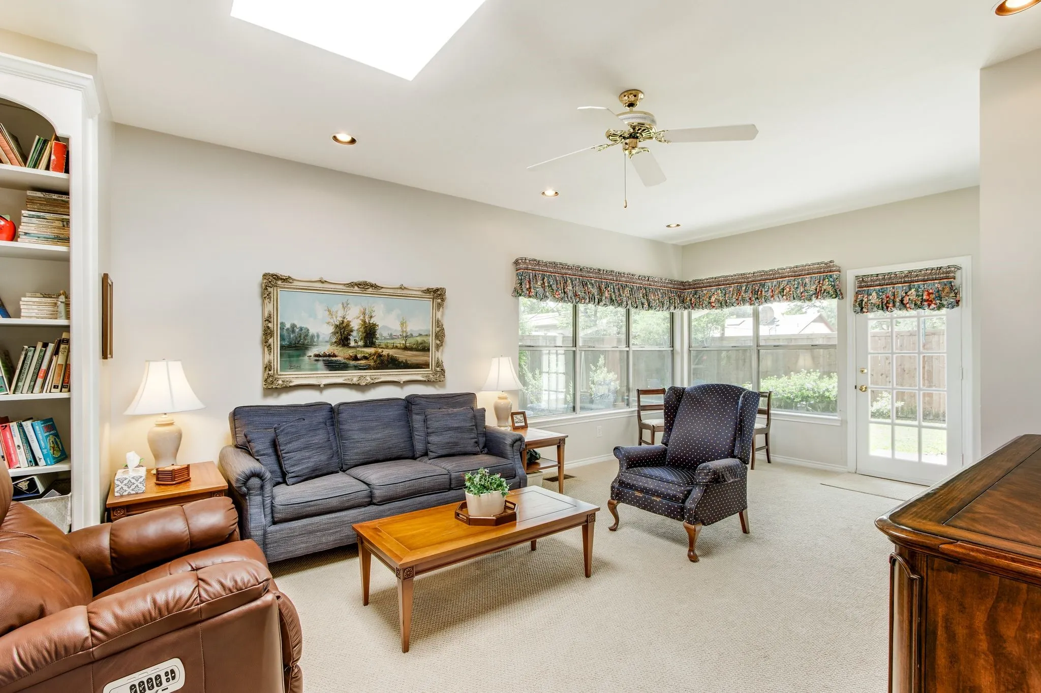 Spacious living area featuring a ceiling fan, recessed lighting, and a skylight